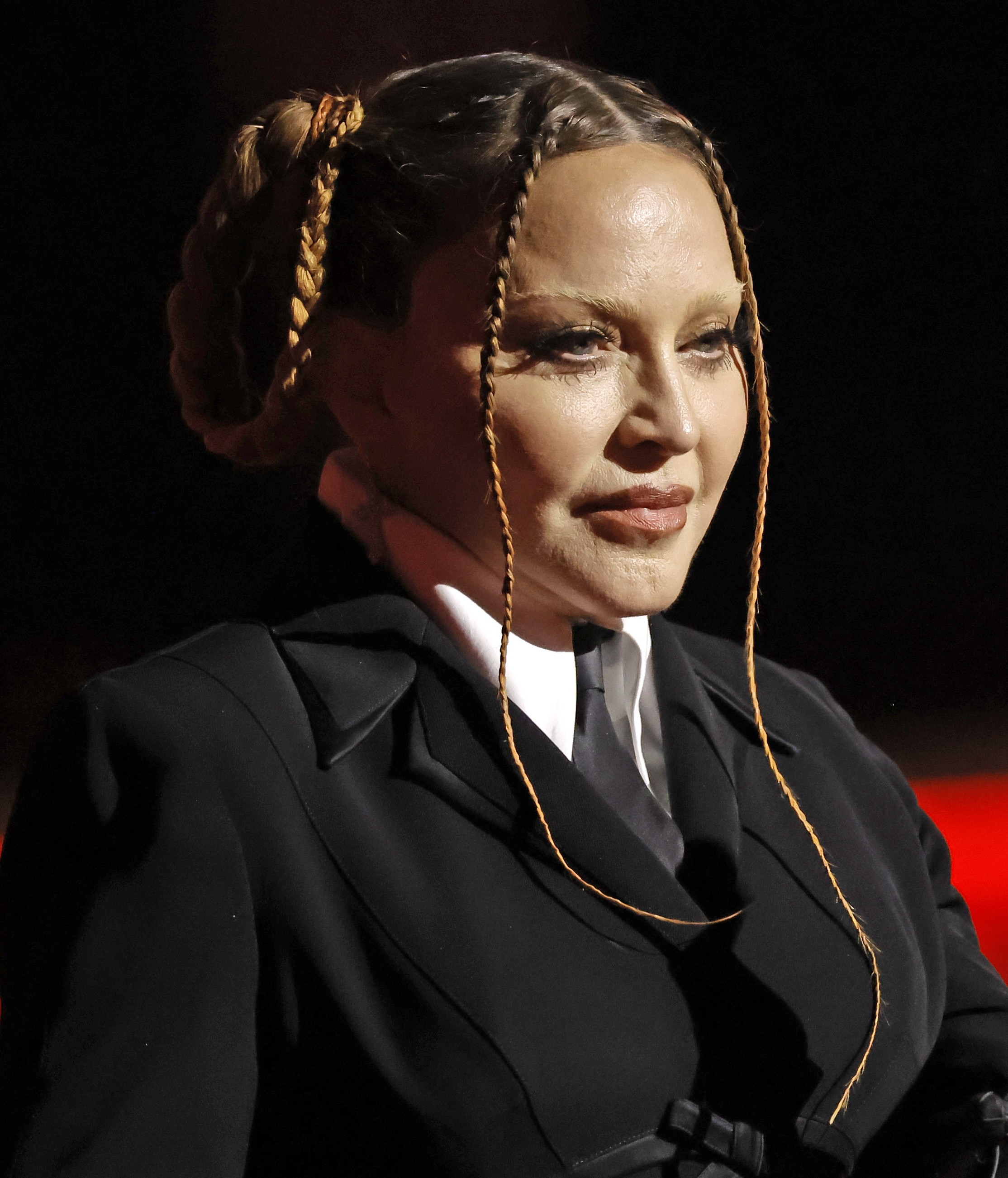 Madonna ist in einem perfekt geschnittenen schwarzen Anzug mit Krawatte zu sehen, ihr Haar ist nach hinten gekämmt und dünne Zöpfe rahmen ihr Gesicht ein. | Quelle: Chat GPT