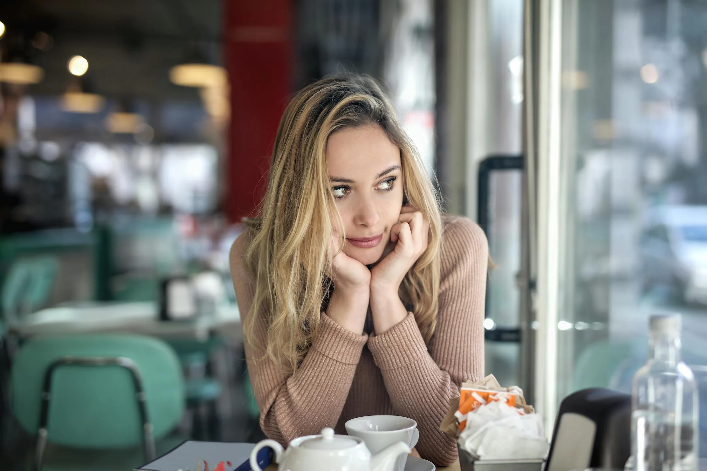 Eine Frau, die in einem Cafe zur Seite schaut | Quelle: Pexels