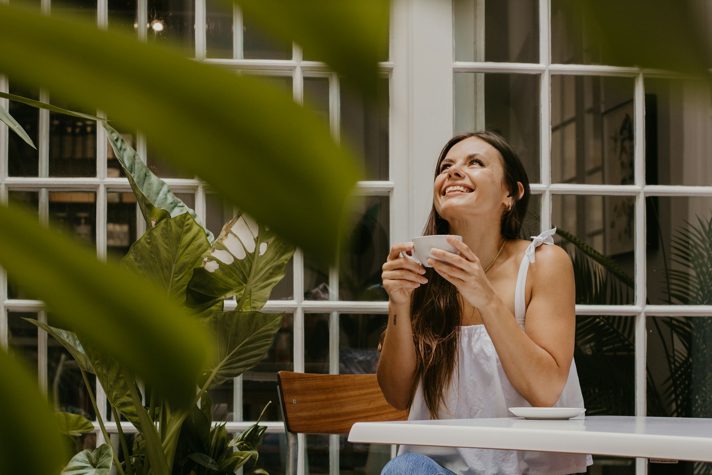 Eine junge Frau lächelt, während sie eine Tasse Kaffee in der Hand hält | Quelle: Unsplash