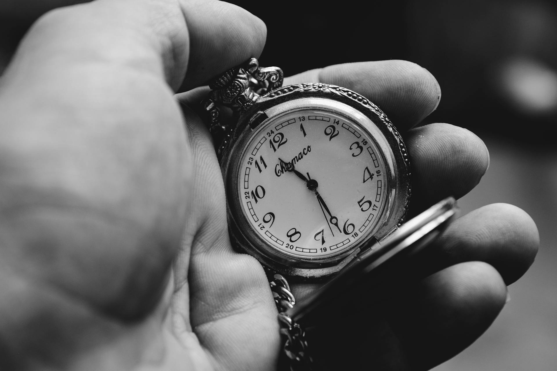 Graustufenaufnahme einer Person, die eine alte Taschenuhr hält | Quelle: Pexels