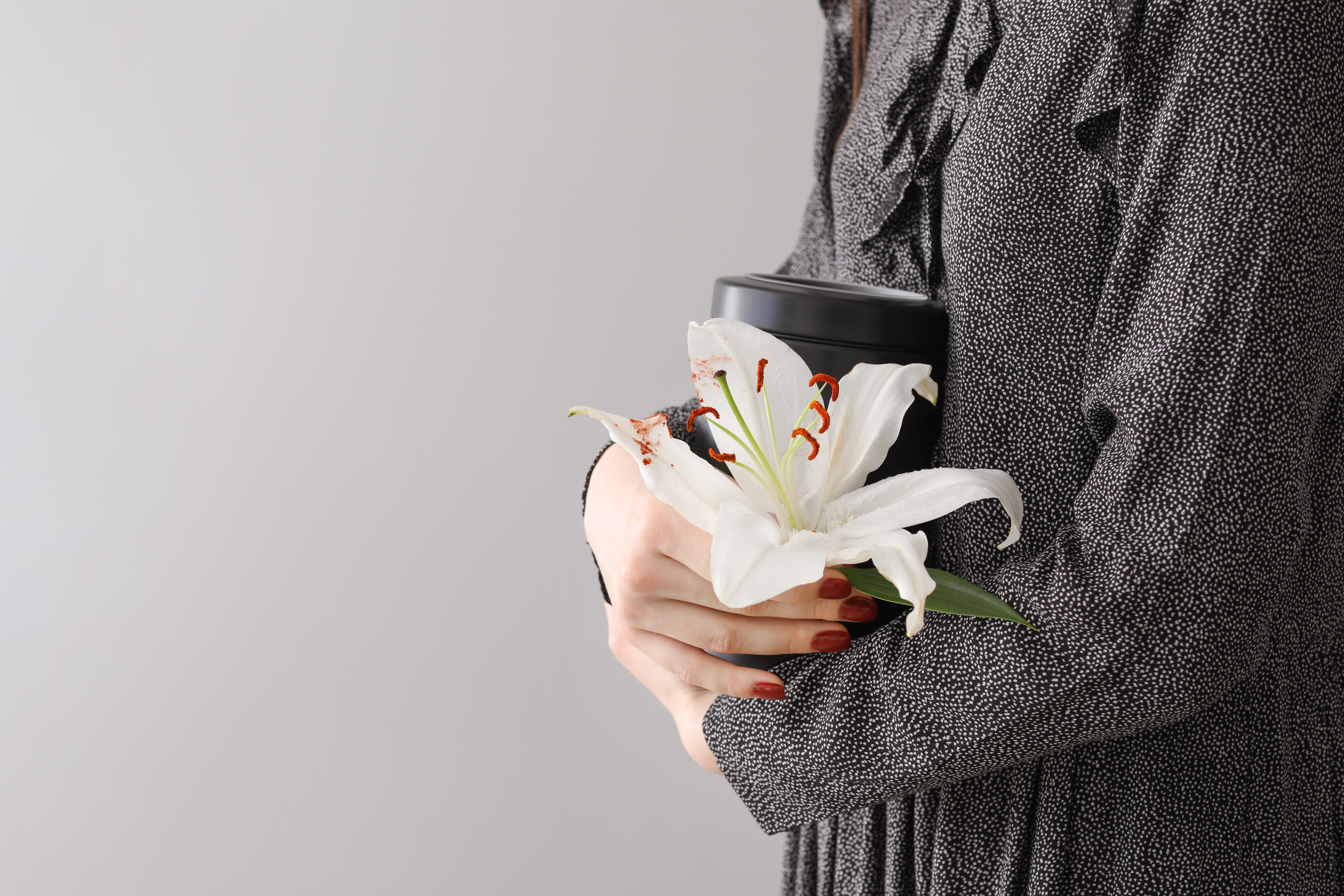 Frau hält eine Urne und eine Lilienblüte | Quelle: Shutterstock