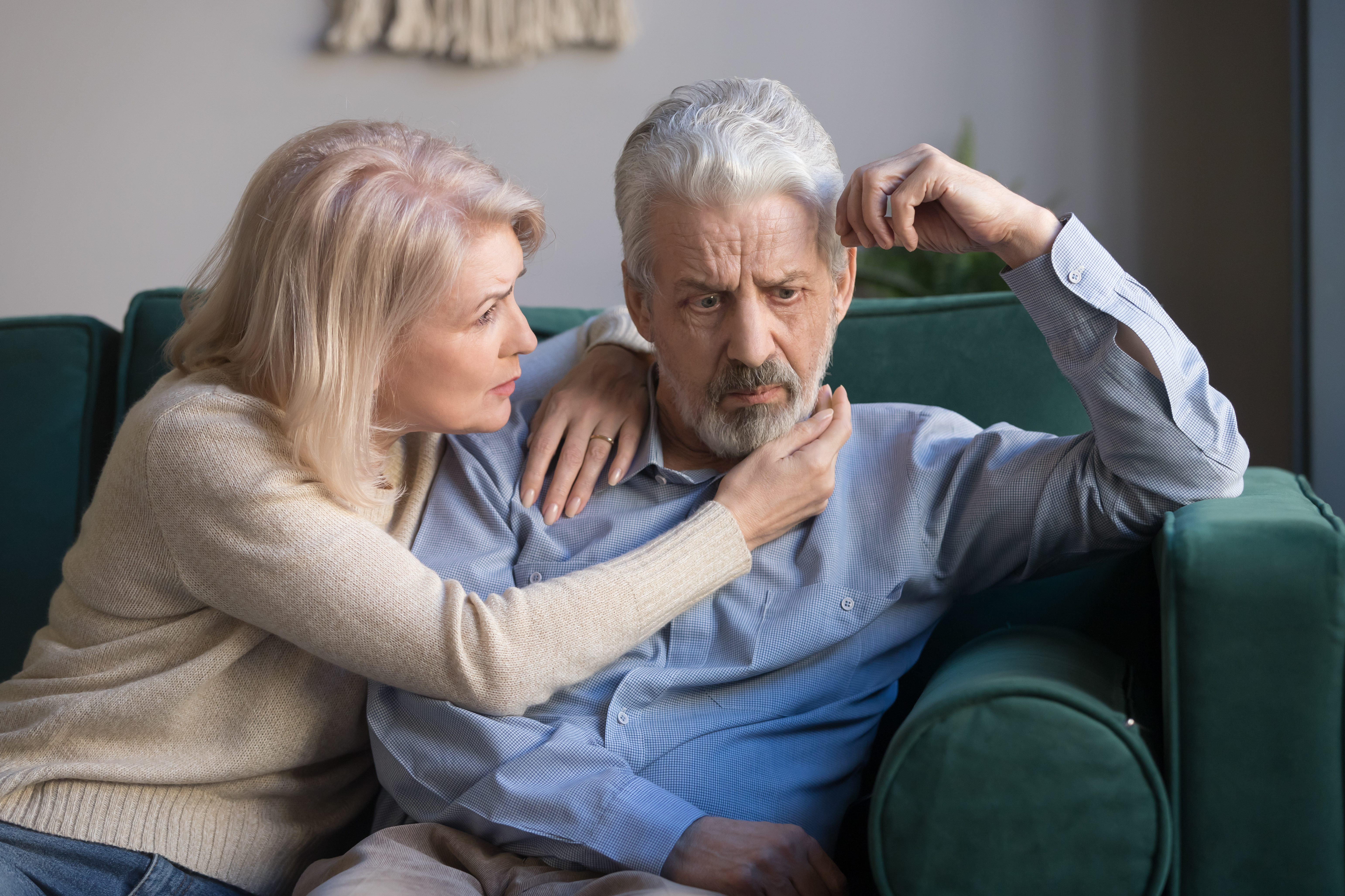 Eine Frau mittleren Alters tröstet ihren aufgebrachten grauhaarigen Mann | Quelle: Shutterstock