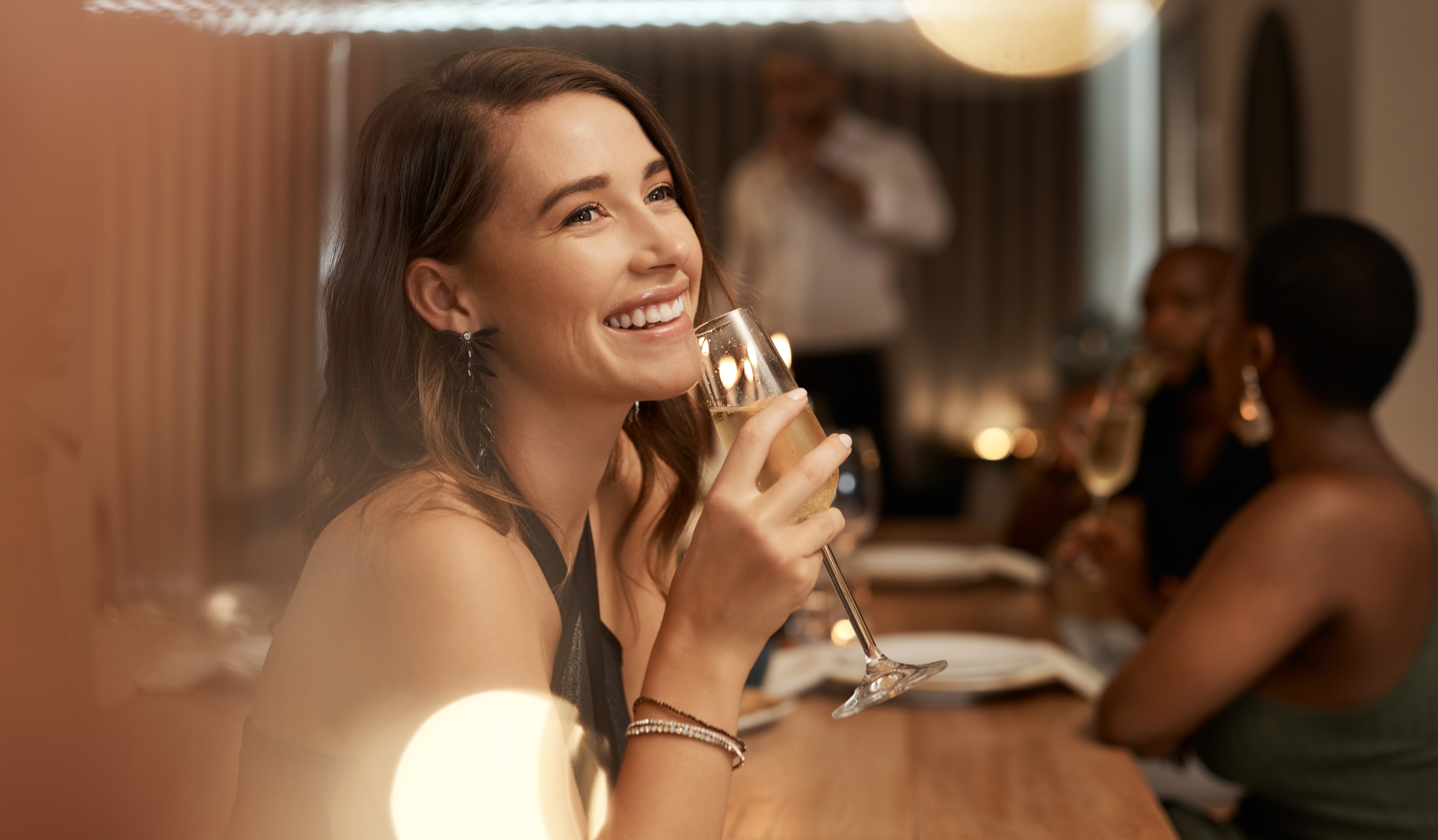 Frau hält ein Glas Champagner in einem Restaurant | Quelle: Shutterstock