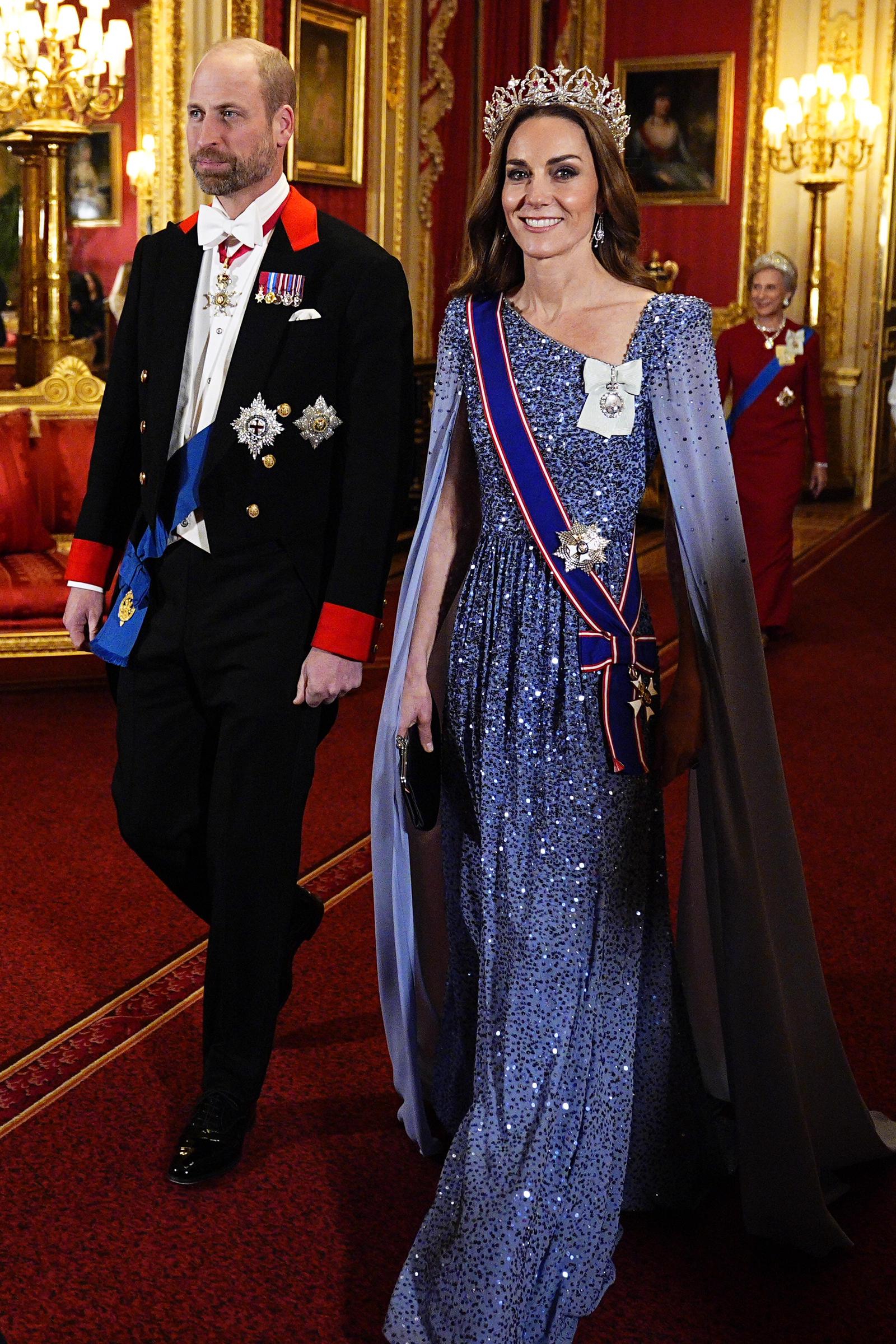 Prinz William und Catherine, Prinzessin von Wales, treffen am 3. Dezember 2025 im Windsor Castle zum Staatsbankett zu Ehren des deutschen Bundespräsidenten Frank-Walter Steinmeier und seiner Frau Elke Büdenbender ein. Catherine strahlt in einem schimmernden, periwinkle-blauen Paillettenkleid von Jenny Packham mit einem bodenlangen, geschlitzten Umhang. Dazu trägt sie die „Strathmore Rose“-Tiara der Königinmutter, die Schärpe des Royal Victorian Order und den Royal Family Order von König Charles III., während William einen formellen Windsor-Frack mit zeremoniellen Auszeichnungen trägt. | Quelle: Getty Images