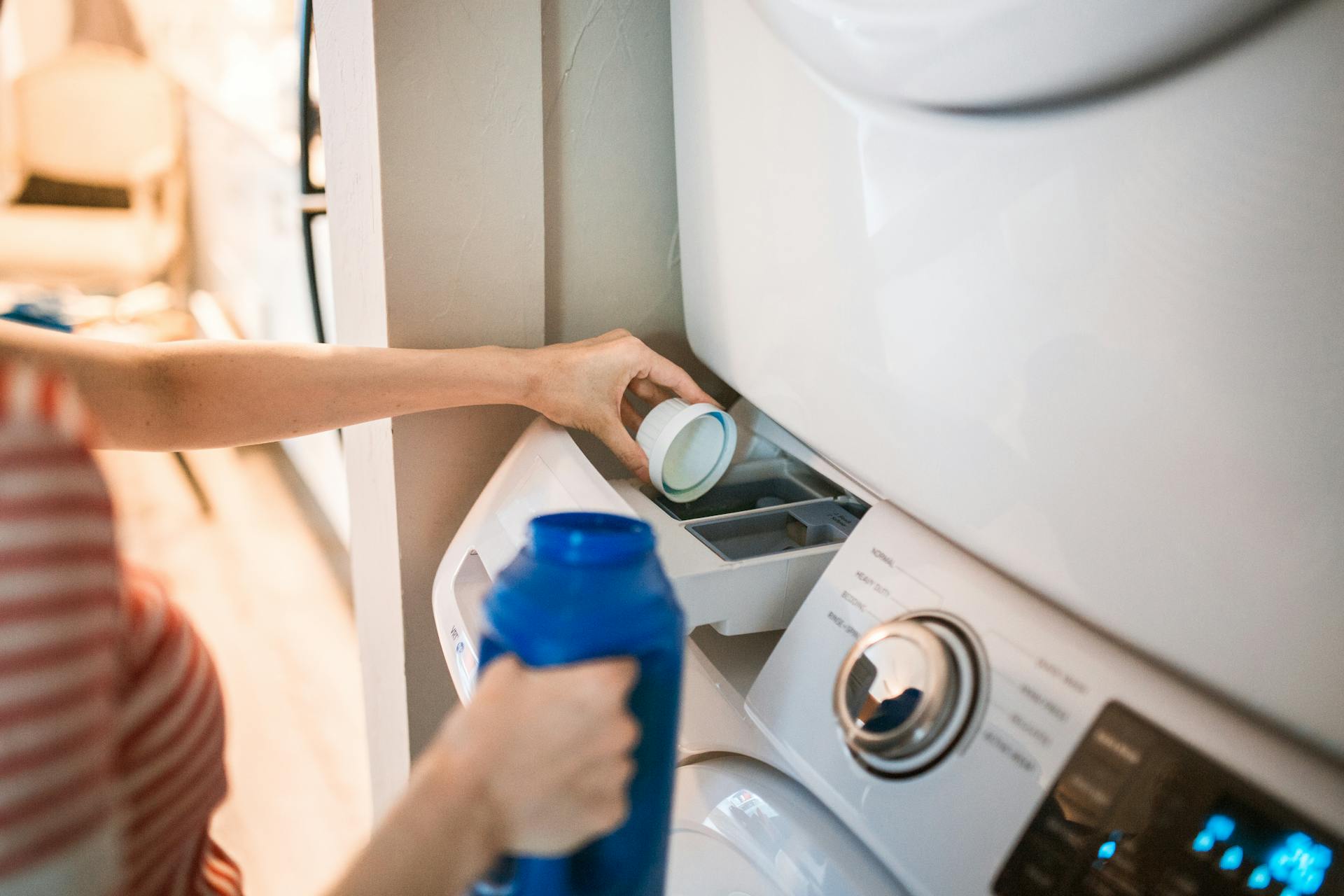 Kobieta wlewająca detergent do pralki | Źródło: Pexels