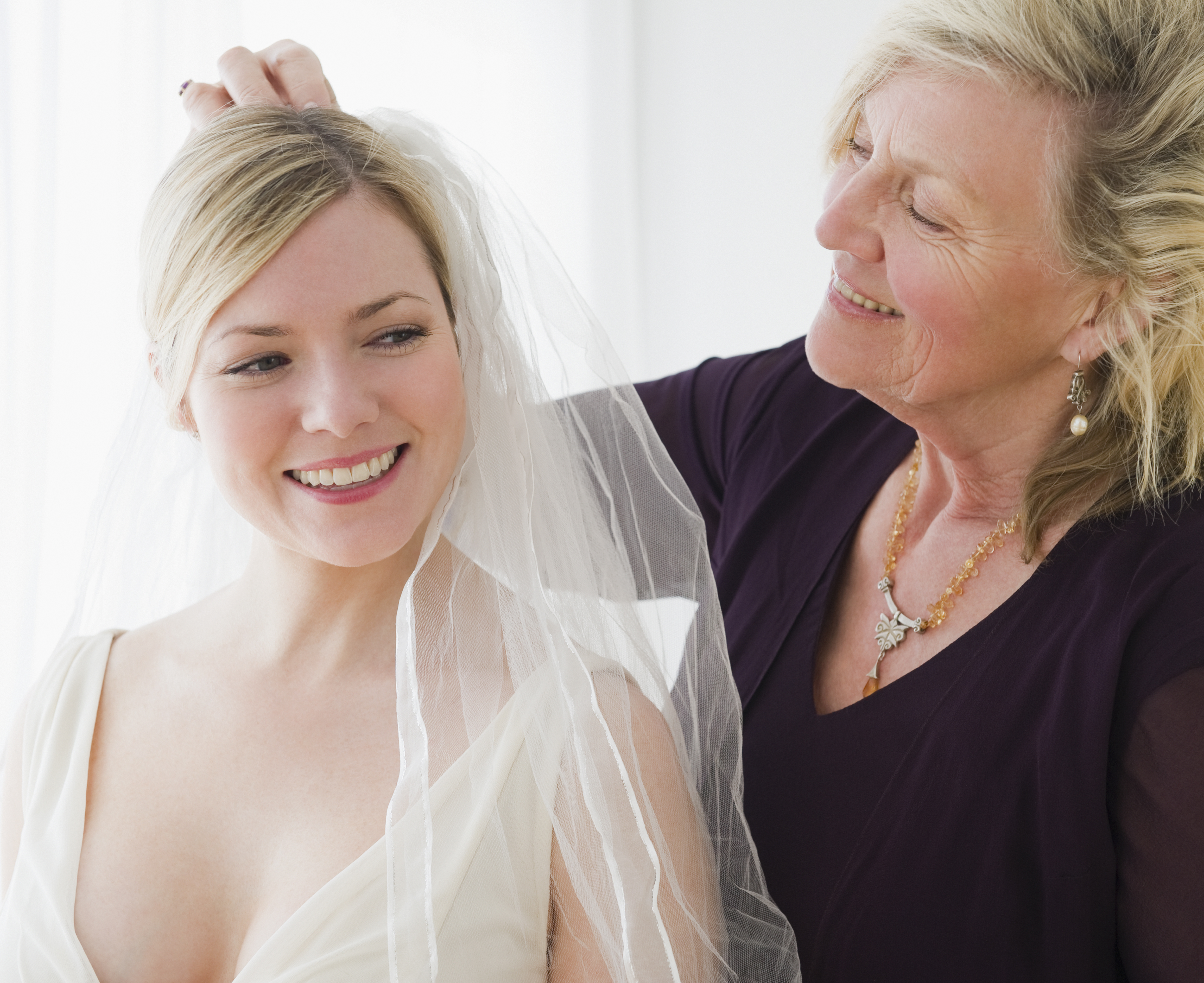 Eine ältere Frau hilft einer jüngeren Frau beim Anprobieren eines Hochzeitskleides | Quelle: Getty Images