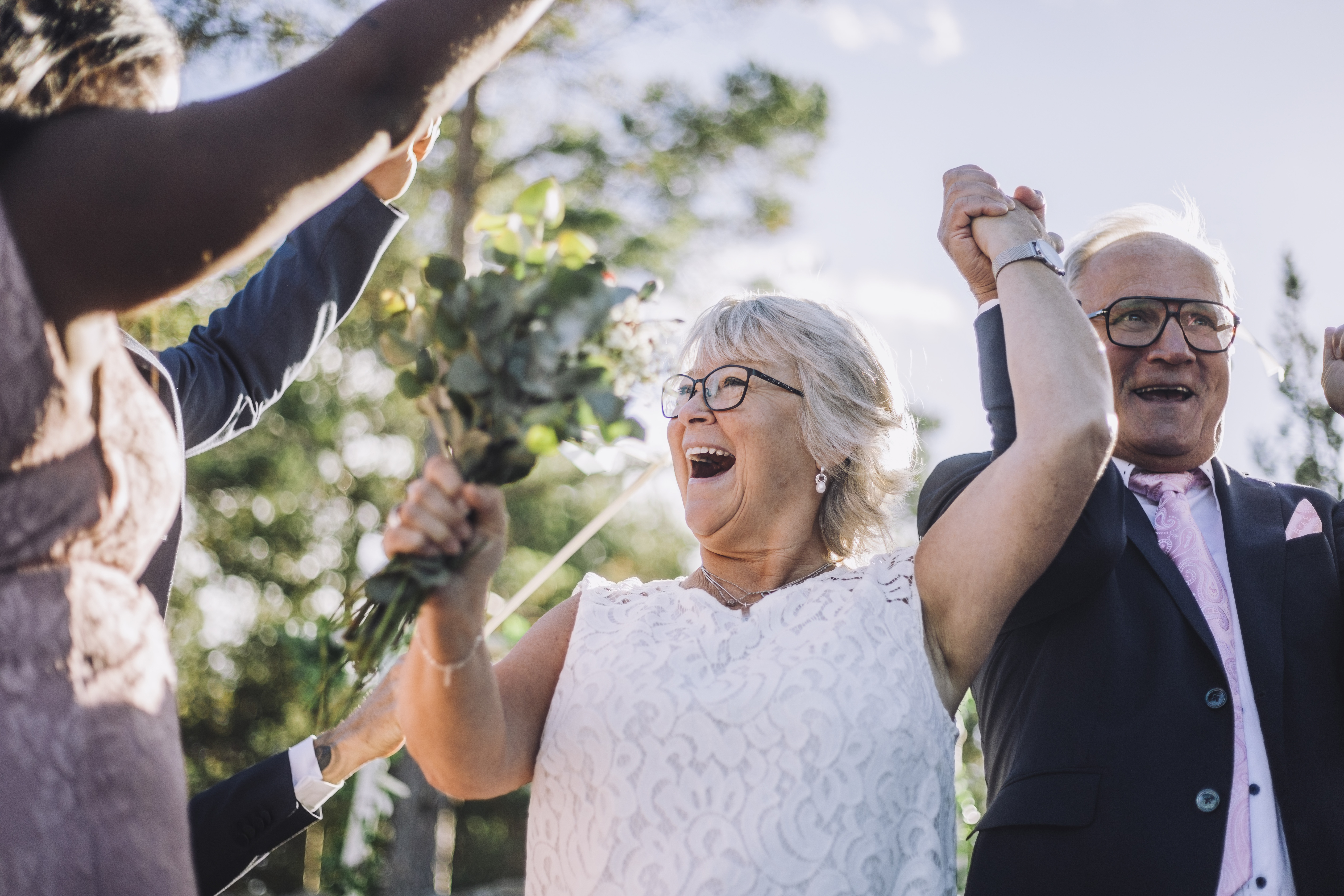 Fröhliches, frisch verheiratetes, älteres Paar hält sich an den Händen und tanzt mit der Familie am Hochzeitstag | Quelle: Getty Images