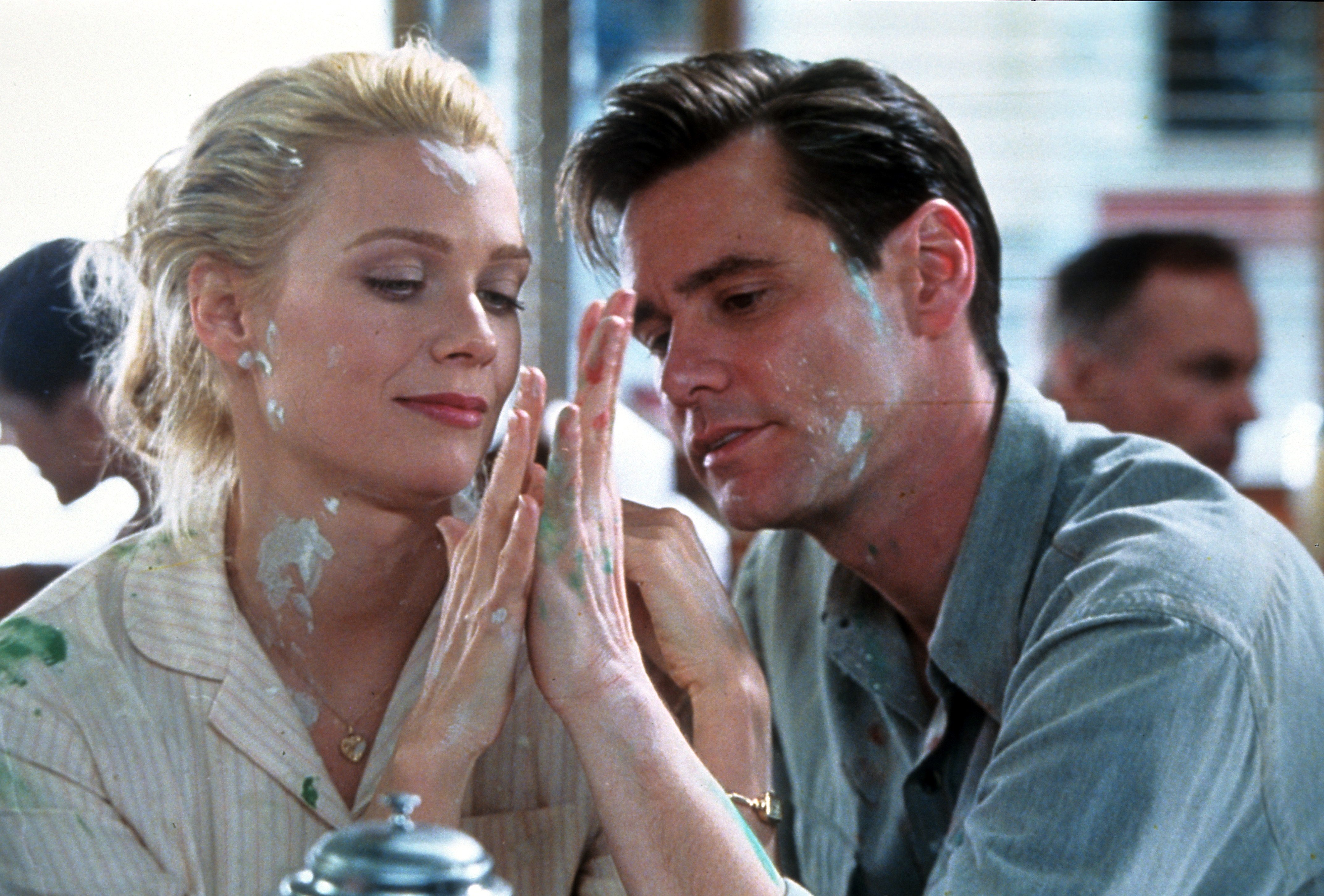 Laurie Holden und Jim Carrey mit weißer Farbe im Gesicht, als sie sich in einer Szene aus dem Film 'The Majestic', 2001, zärtlich die Hände reichen. | Quelle: Getty Images