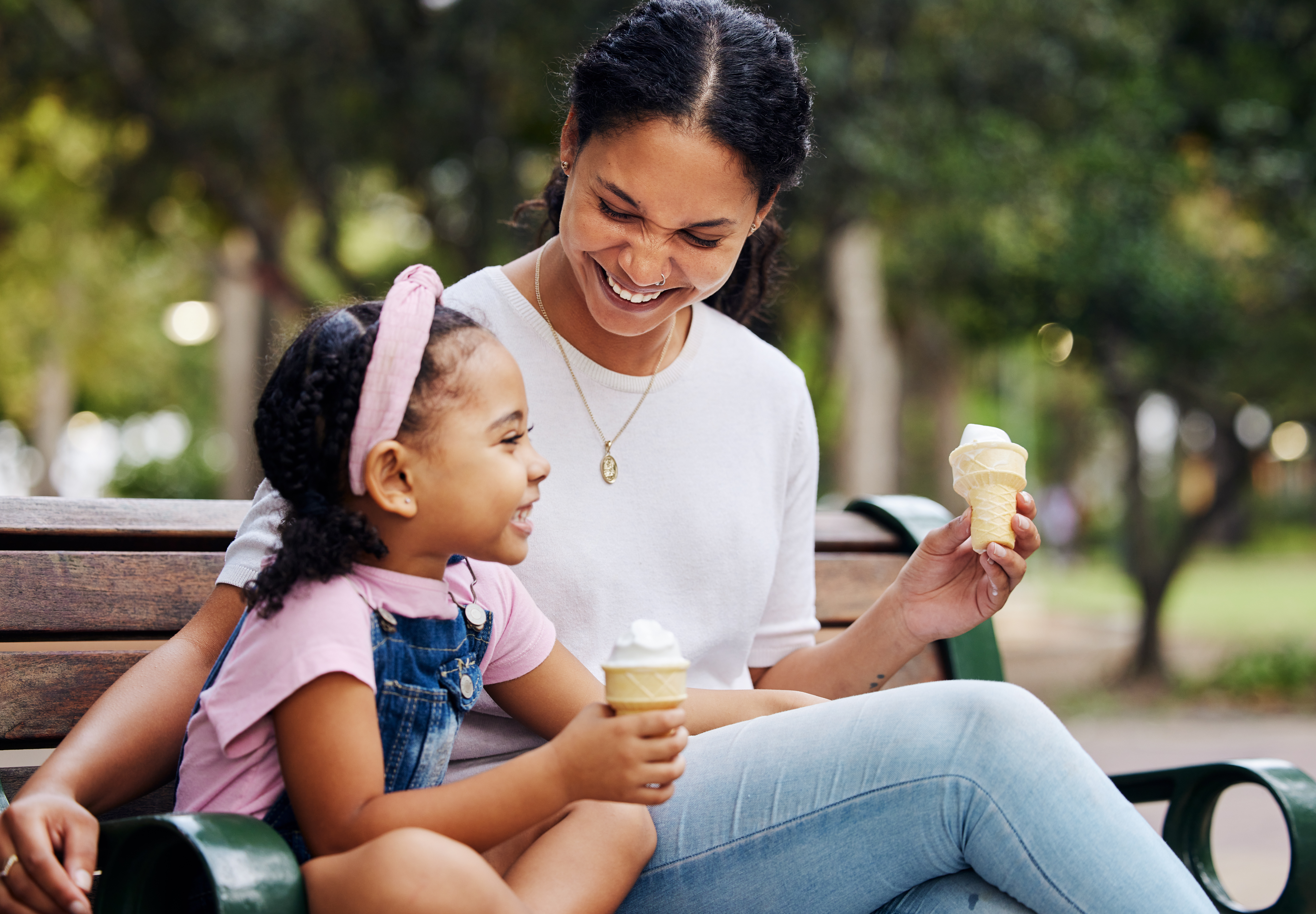 Eine Mutter und ihre Tochter essen ein Eis auf einer Parkbank | Quelle: Getty Images