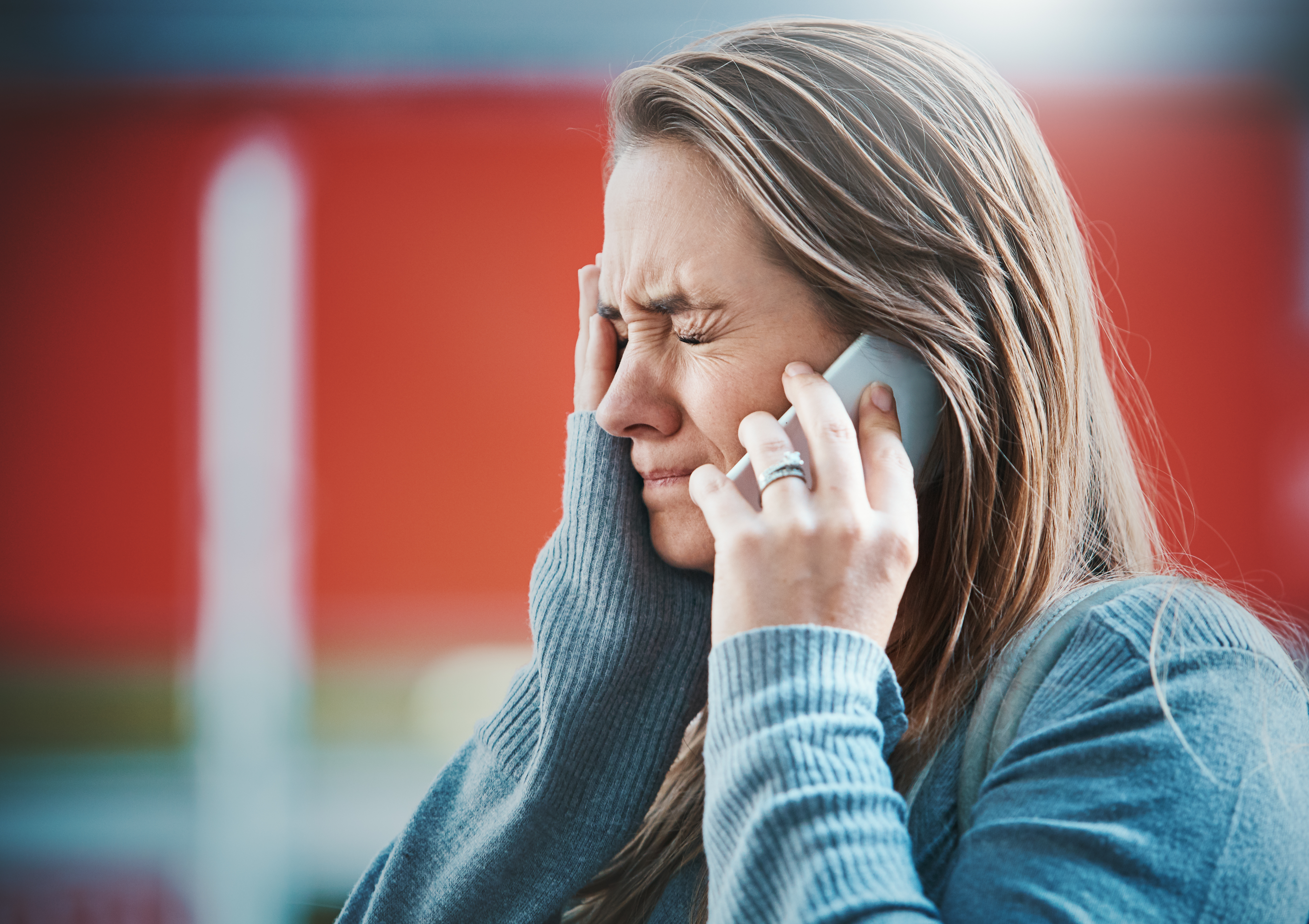 Junge Frau hält am Telefon die Tränen zurück | Quelle: Getty Images