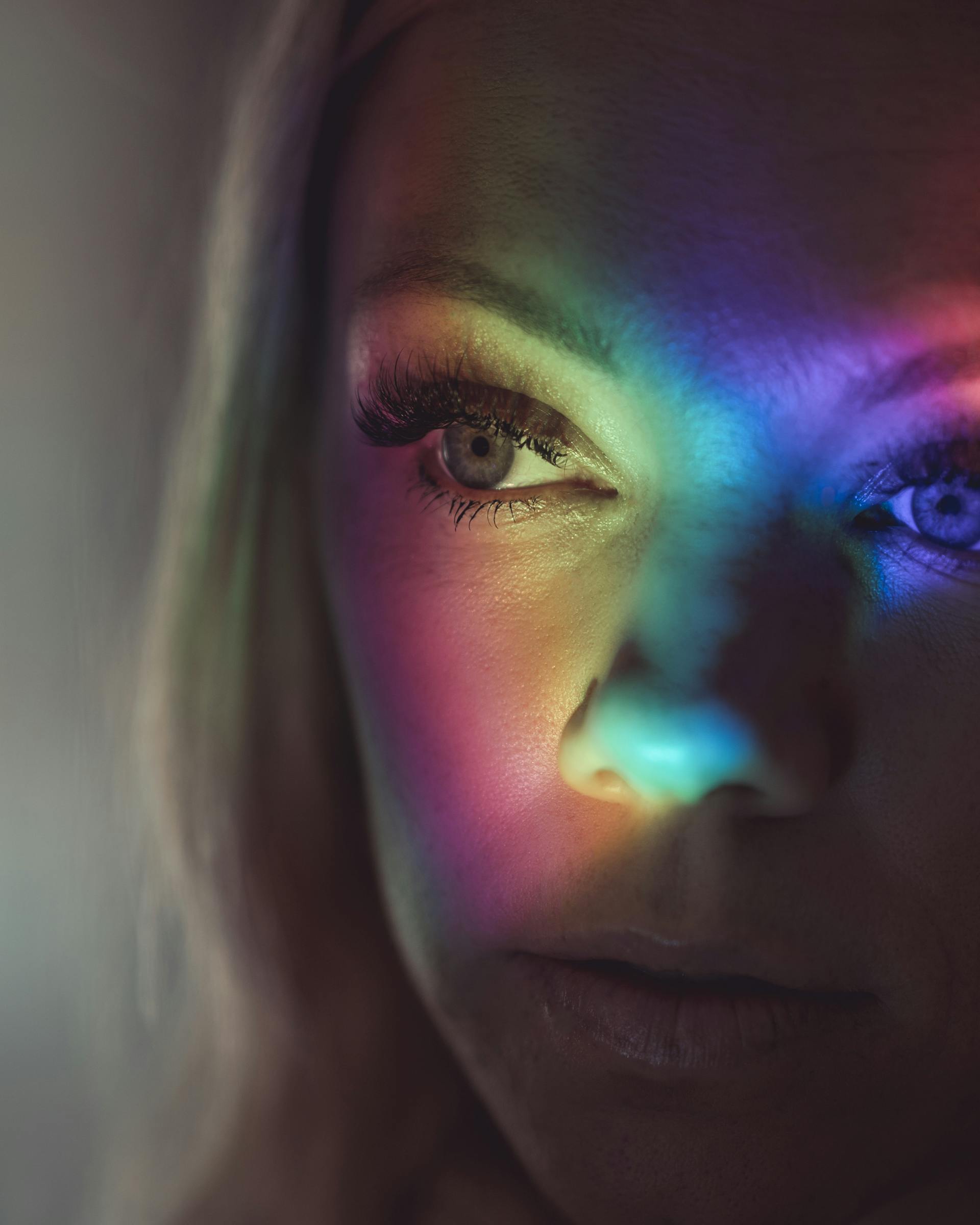 Das Gesicht einer schönen Frau, beleuchtet von bunten Lichtern | Quelle: Pexels