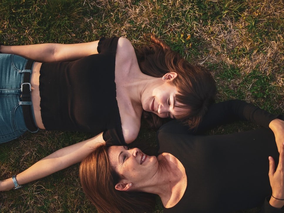 Two women are lying in the grass  Source: Unsplash