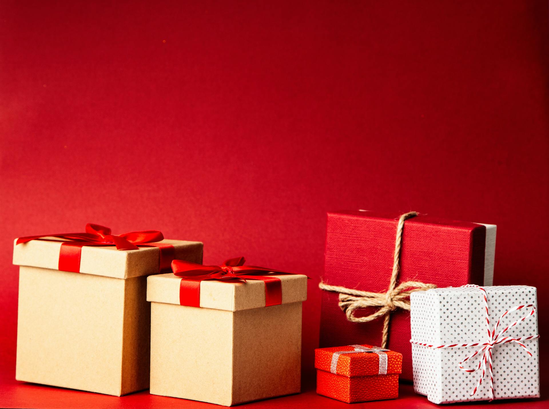 Eine Sammlung von Geschenkboxen vor einem roten Hintergrund | Quelle: Pexels