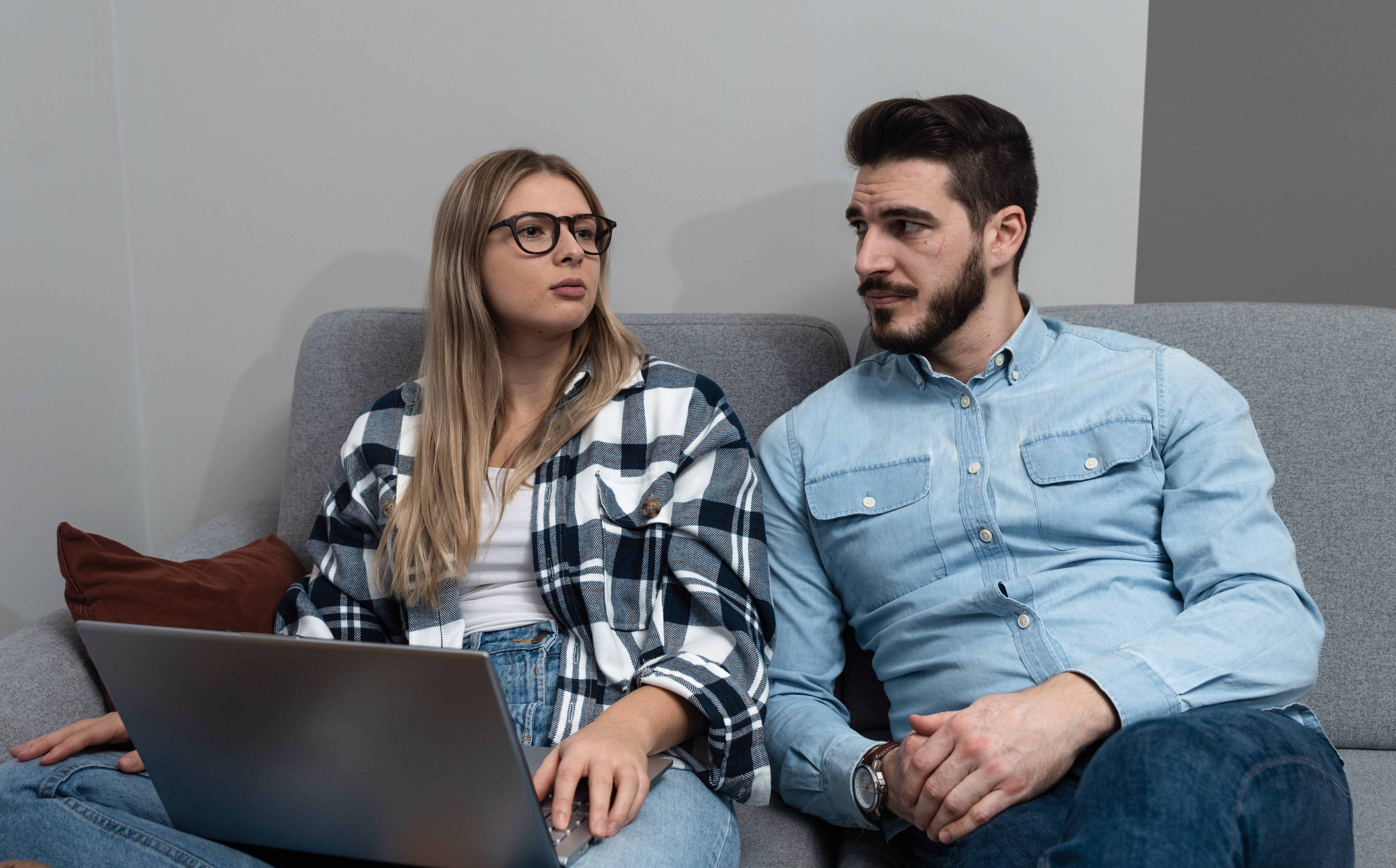 Ein Paar, das zusammensitzt und etwas bespricht, während ein Laptop auf dem Schoß der Frau liegt | Quelle: Shutterstock