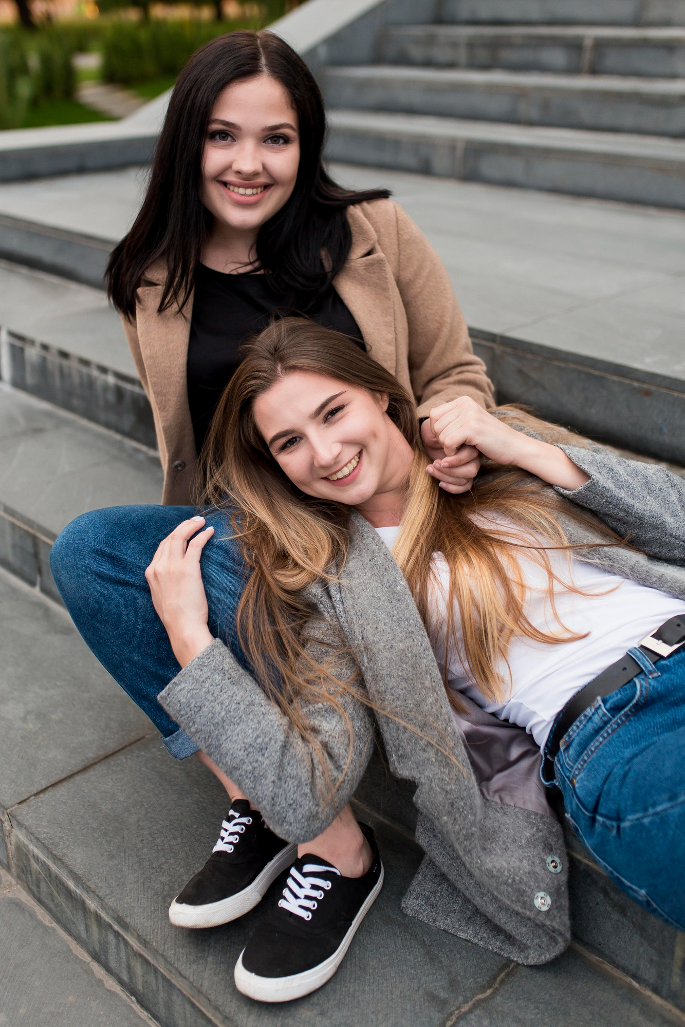 Zwei glückliche junge Frauen, die sich draußen auf einer Treppe treffen | Quelle: Freepik