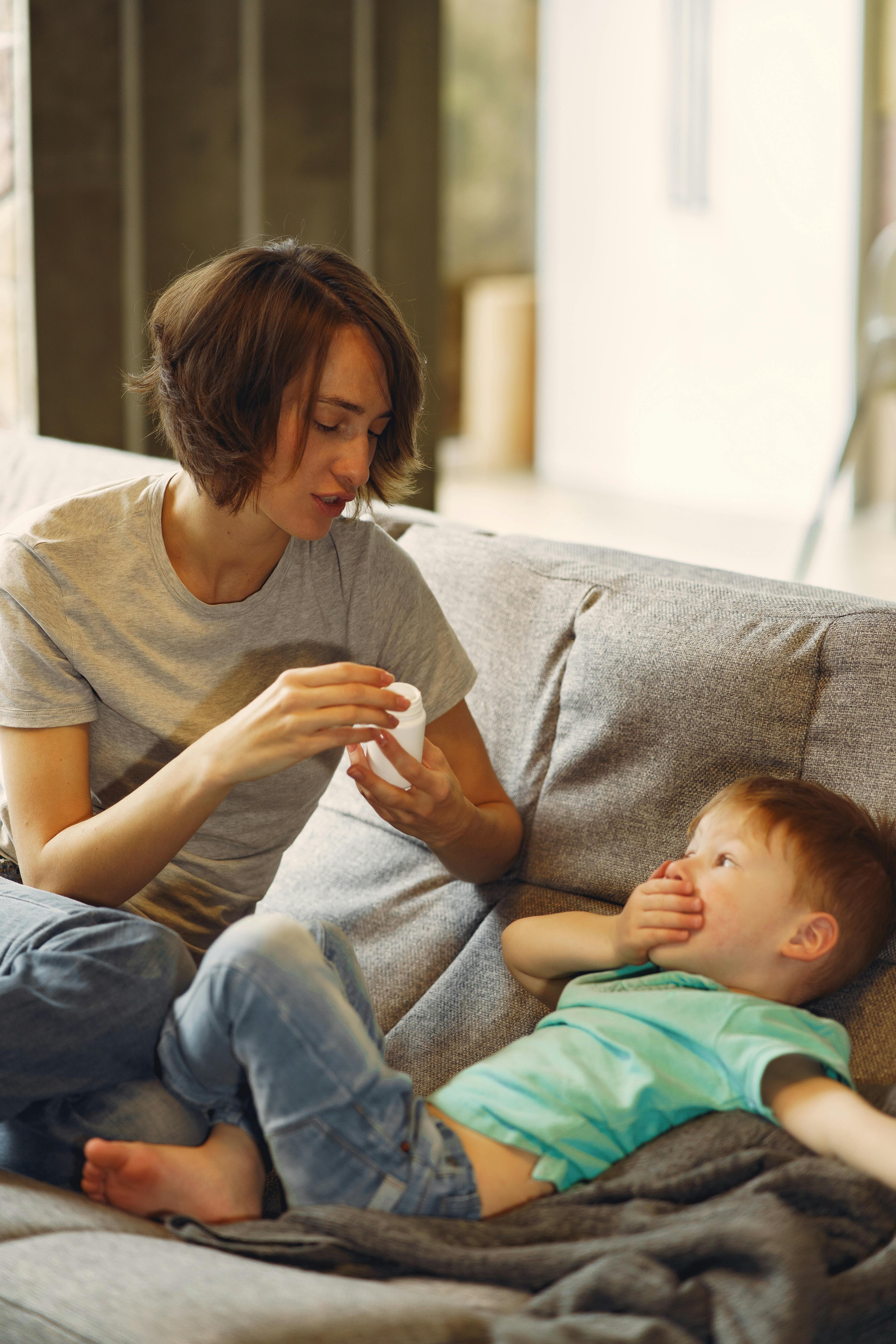 Kleiner Junge mit seiner Mutter auf der Couch, die Hand auf dem Mund | Quelle: Pexels