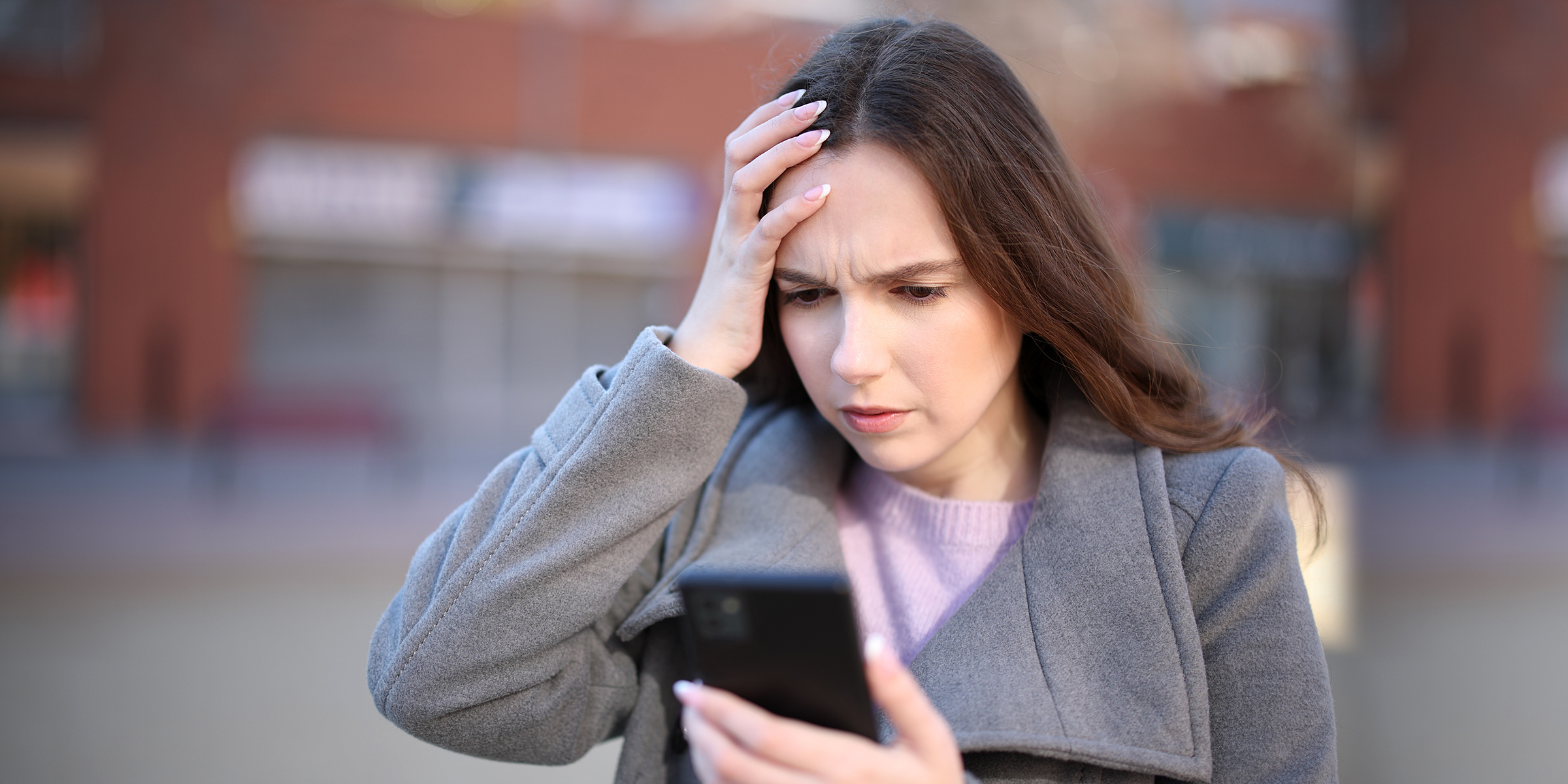 Eine schockierte Frau, die auf ihr Telefon schaut | Quelle: Shutterstock