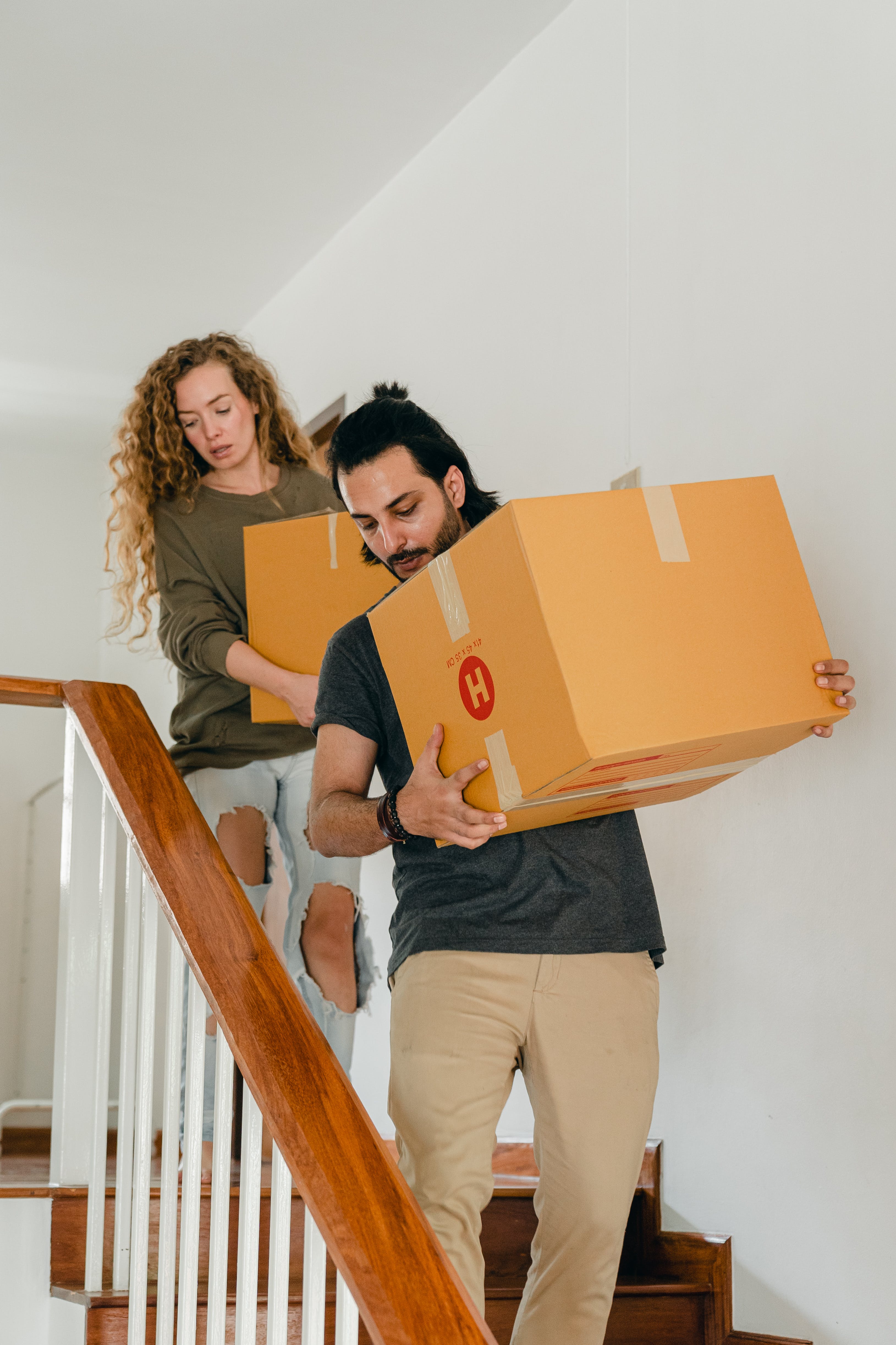 Ein junges Paar trägt Kisten, während es die Treppe hinuntergeht | Quelle: Pexels