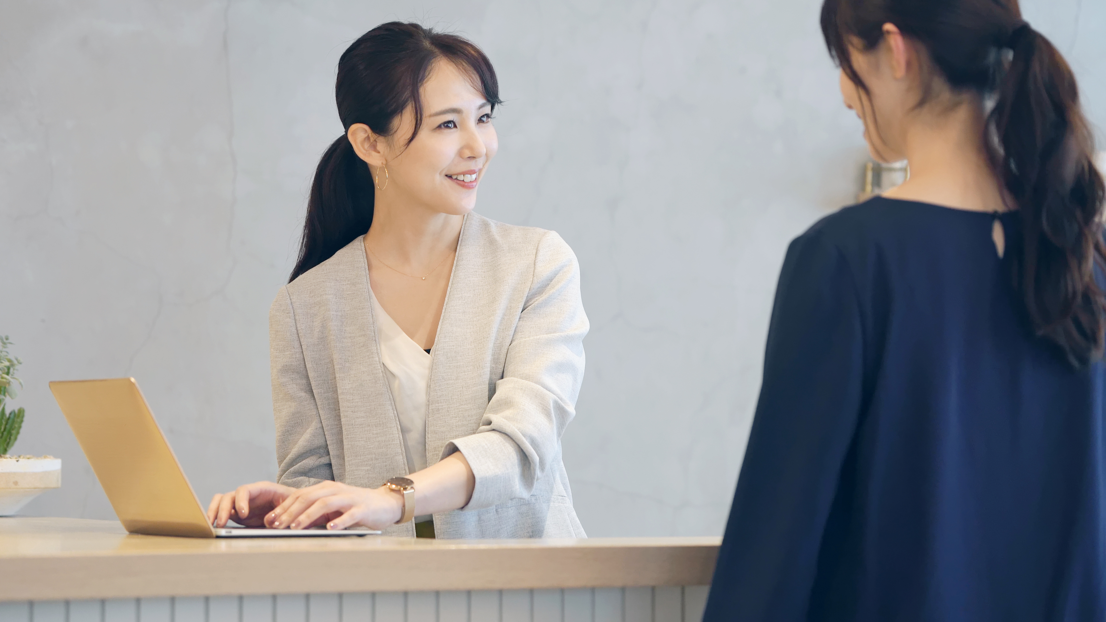 Eine Frau im Gespräch mit einer asiatischen Empfangsdame | Quelle: Shutterstock