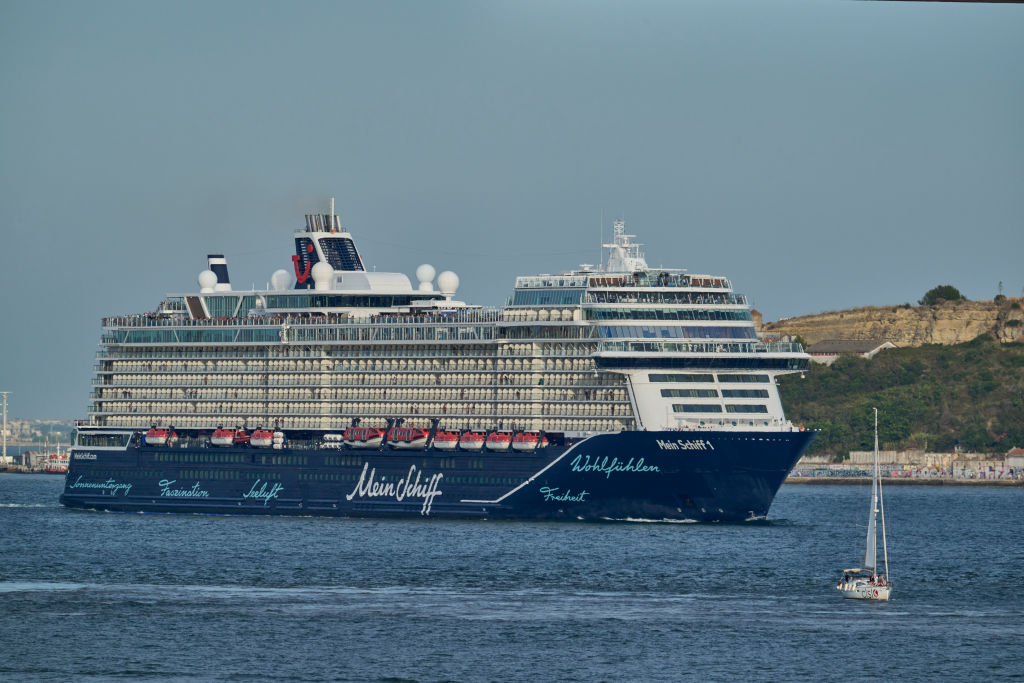 Die Passagiere stehen dicht gedrängt auf den Oberdecks, während die TUI Mein Schiff 1, ein Kreuzfahrtschiff von TUI Cruises, am 17. August 2023 in Lissabon den Kreuzfahrtterminal verlässt und den Tejo hinauffährt. | Quelle: Getty Images