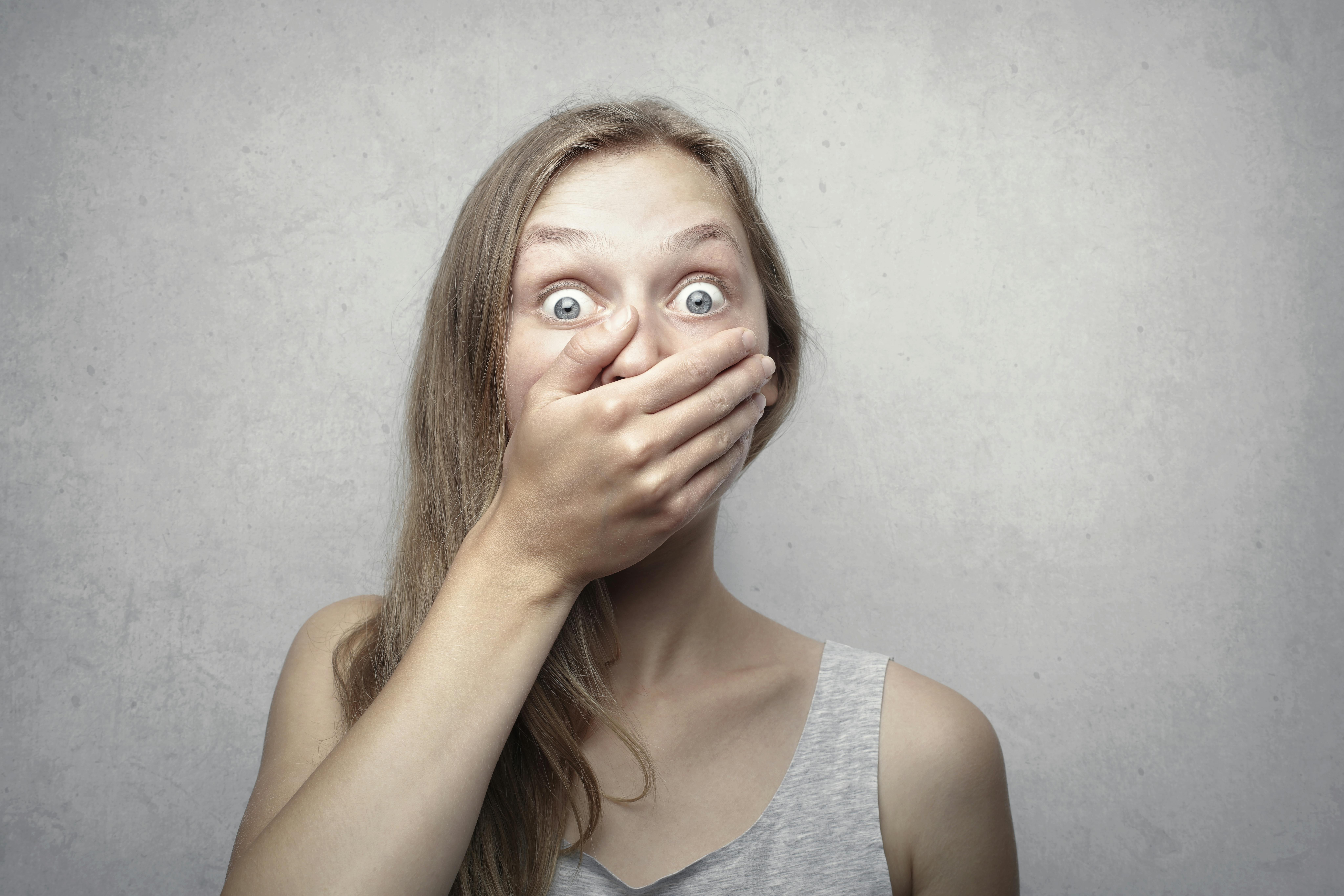 Eine Frau hält sich den Mund zu, während sie schockiert aussieht | Quelle: Pexels