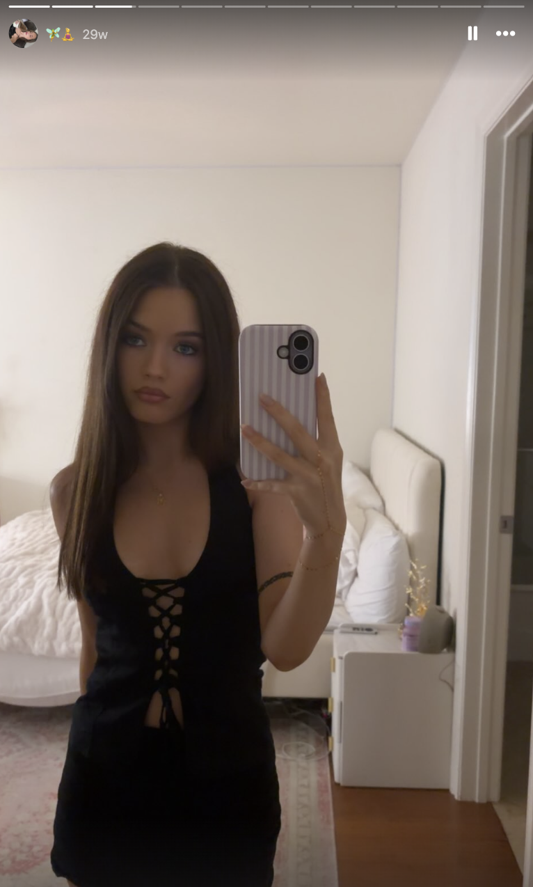 Harper Lockwood macht ein Selfie vor dem Spiegel im Schlafzimmer – sie trägt ein schwarzes Neckholder-Top mit Schnürung und hat ihr langes braunes Haar glatt gestylt und in der Mitte gescheitelt. | Quelle: Instagram/harper.lockwoodd