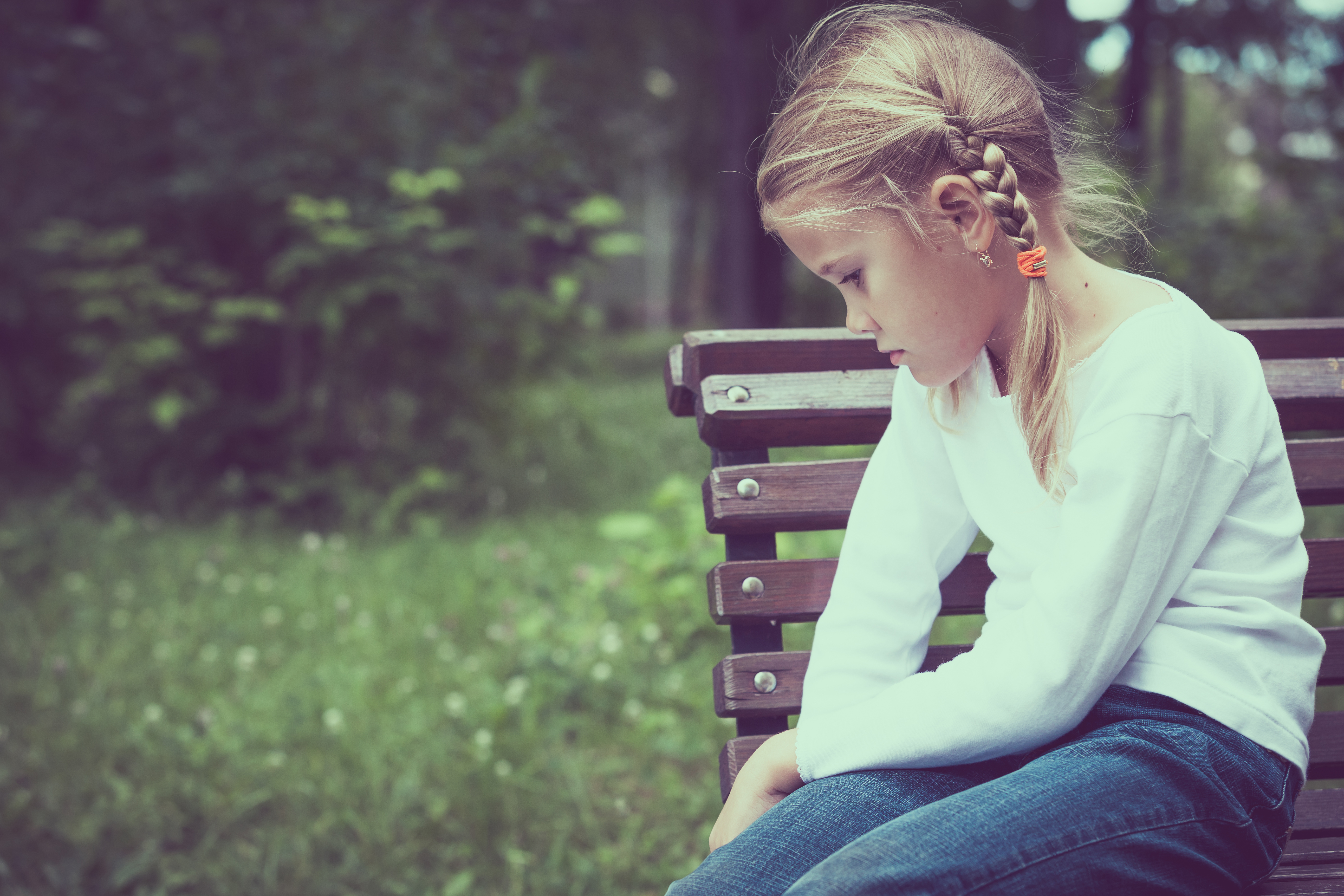 Ein kleines Mädchen sitzt auf einer Bank | Quelle: Shutterstock