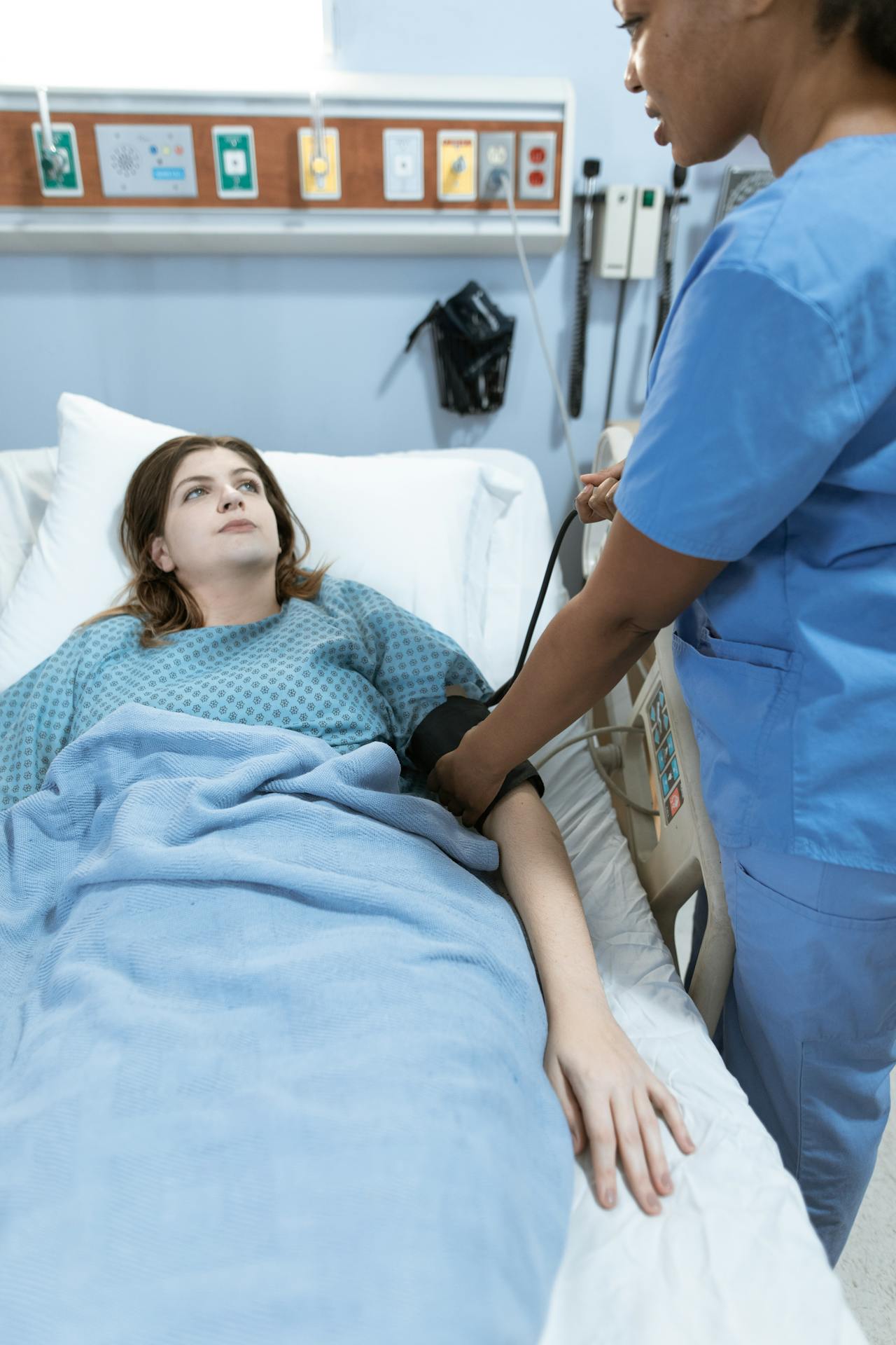 Eine Frau liegt in einem Krankenhausbett und schaut die Krankenschwester an | Quelle: Pexels