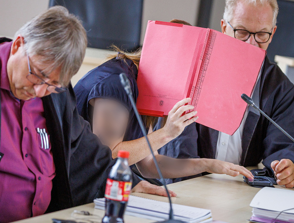 Die Angeklagte sitzt zwischen ihren Anwälten Andreas Ohm (l.) und Thomas Löcker (r.) im Gerichtssaal des Landgerichts Rostock, 1. Juli 2026. | Quelle: Getty Images