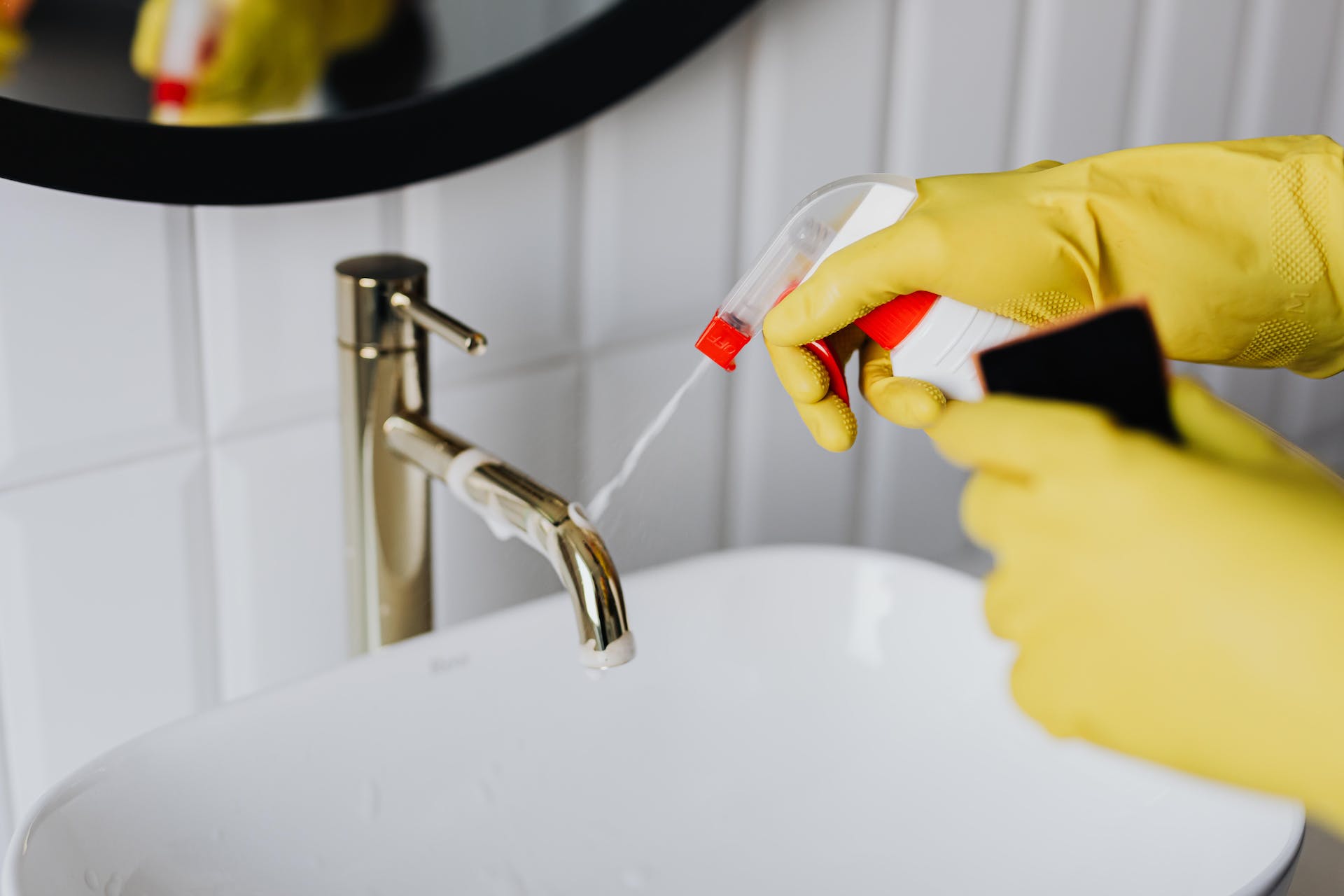 Person, die das Badezimmer mit gelben Handschuhen putzt | Quelle: Pexels