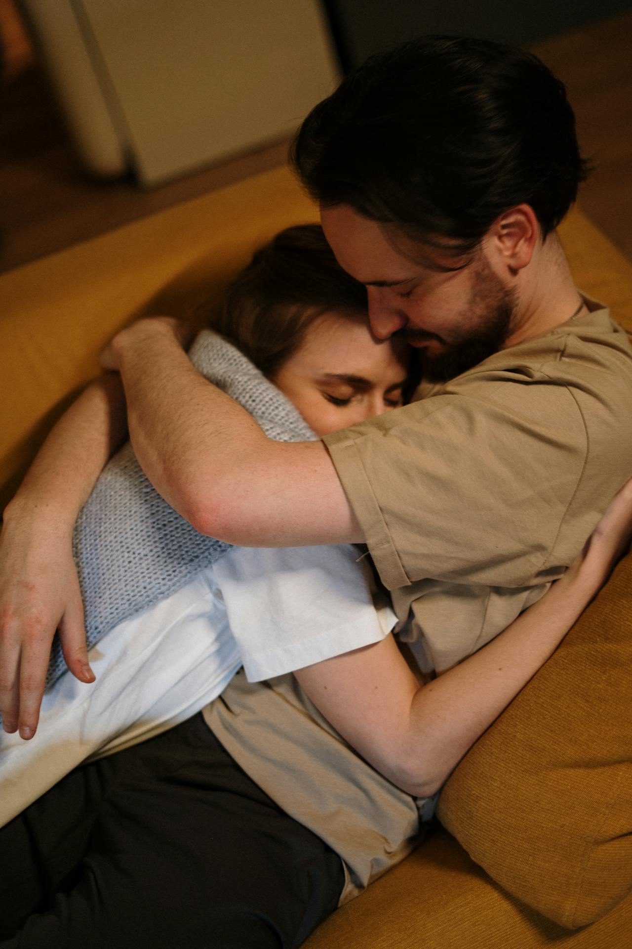 Ein Paar, das sich umarmt, während es auf der Couch liegt | Quelle: Pexels