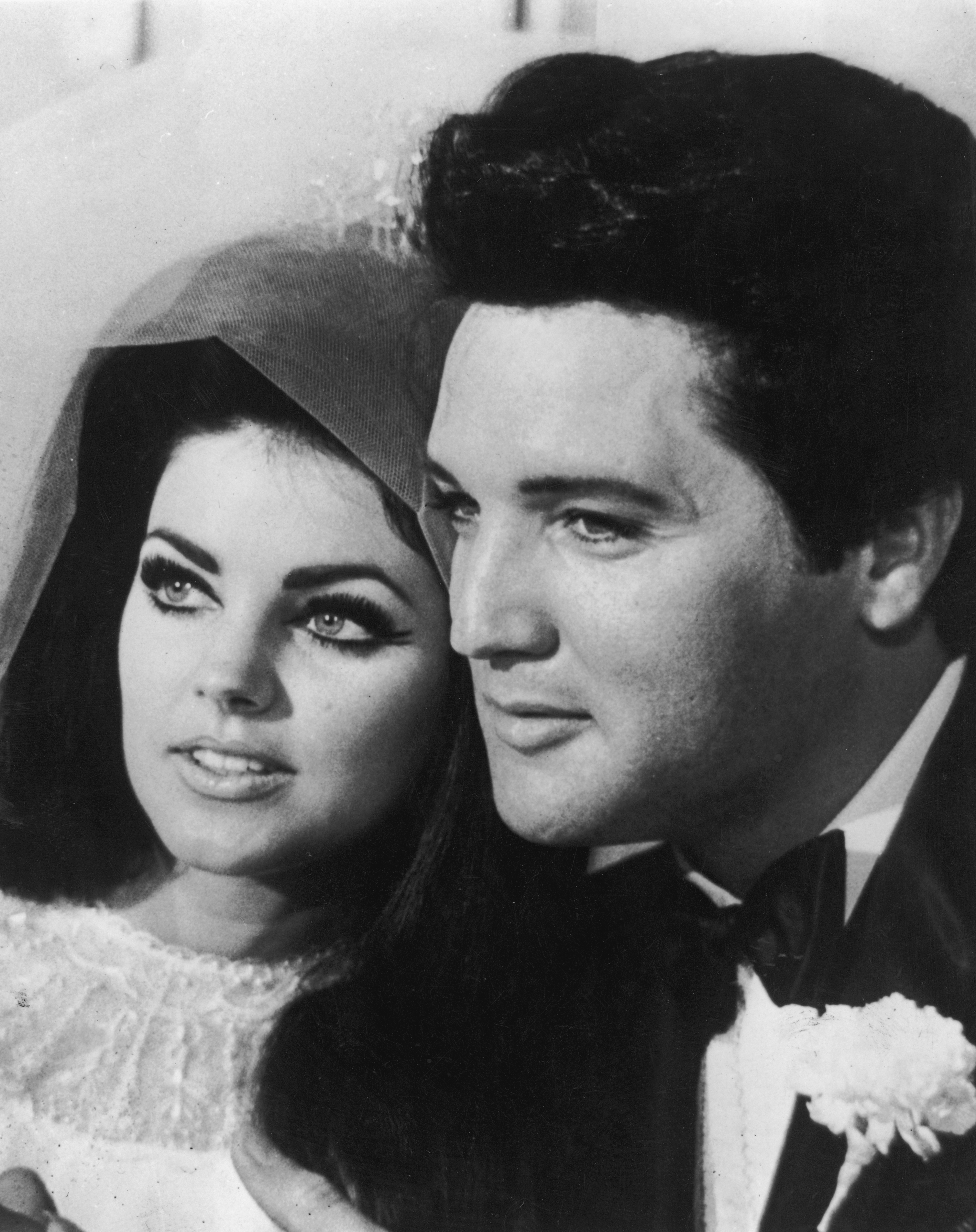 Priscilla Beaulieu posiert eng an der Seite ihres frischgebackenen Ehemanns Elvis Presley nach ihrer Hochzeitszeremonie in Las Vegas am 1. Mai 1967. Zu sehen ist ihre auffällige Hochsteckfrisur mit Schleier und perlenbesetzter Brautspitze neben Elvis im klassischen schwarzen Smoking, mit Fliege und weißer Blumen-Ansteckblume. | Quelle: Getty Images