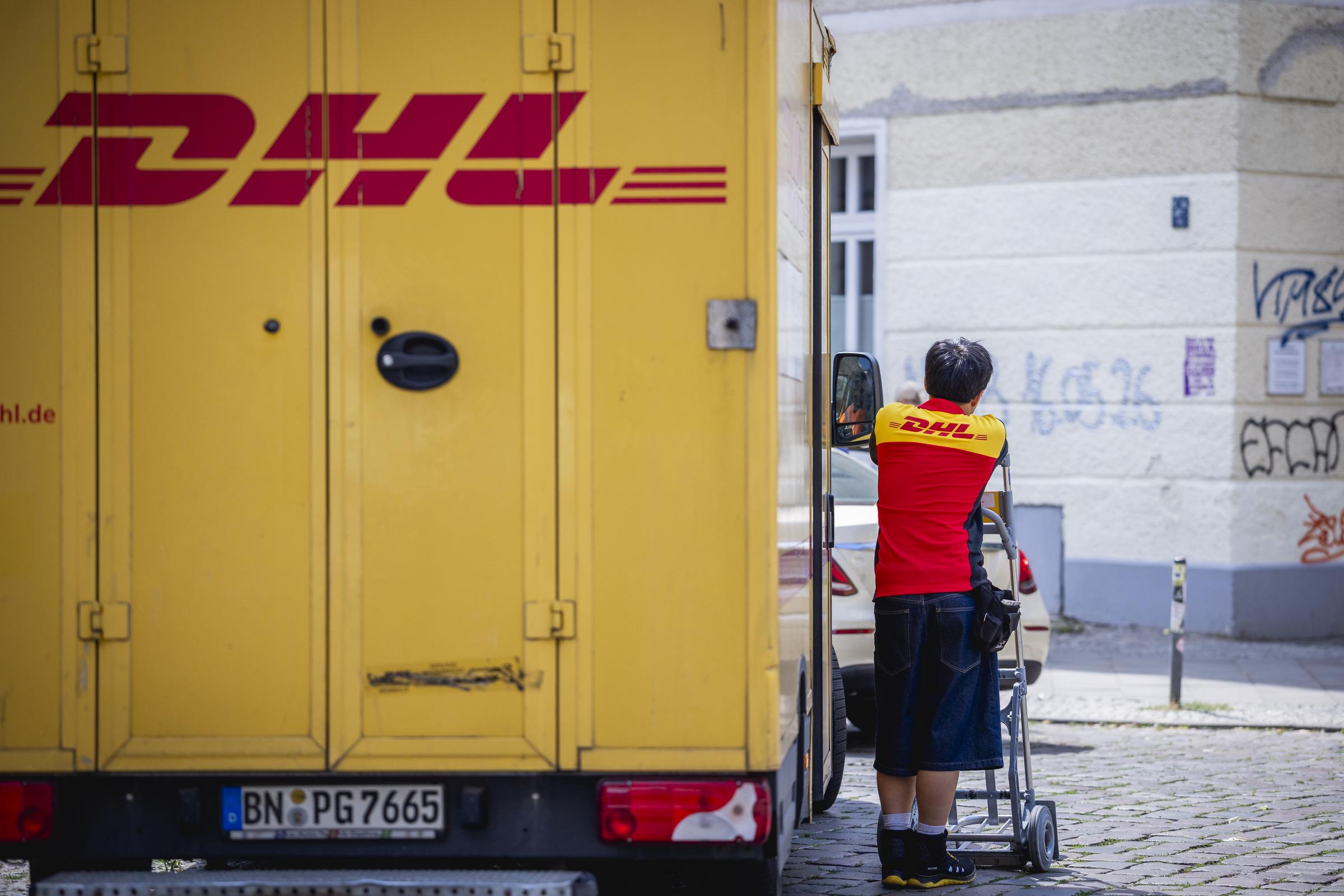Ein Paketzusteller neben einem DHL-Fahrzeug. Zu Illustrationszwecken. | Quelle: Getty Images