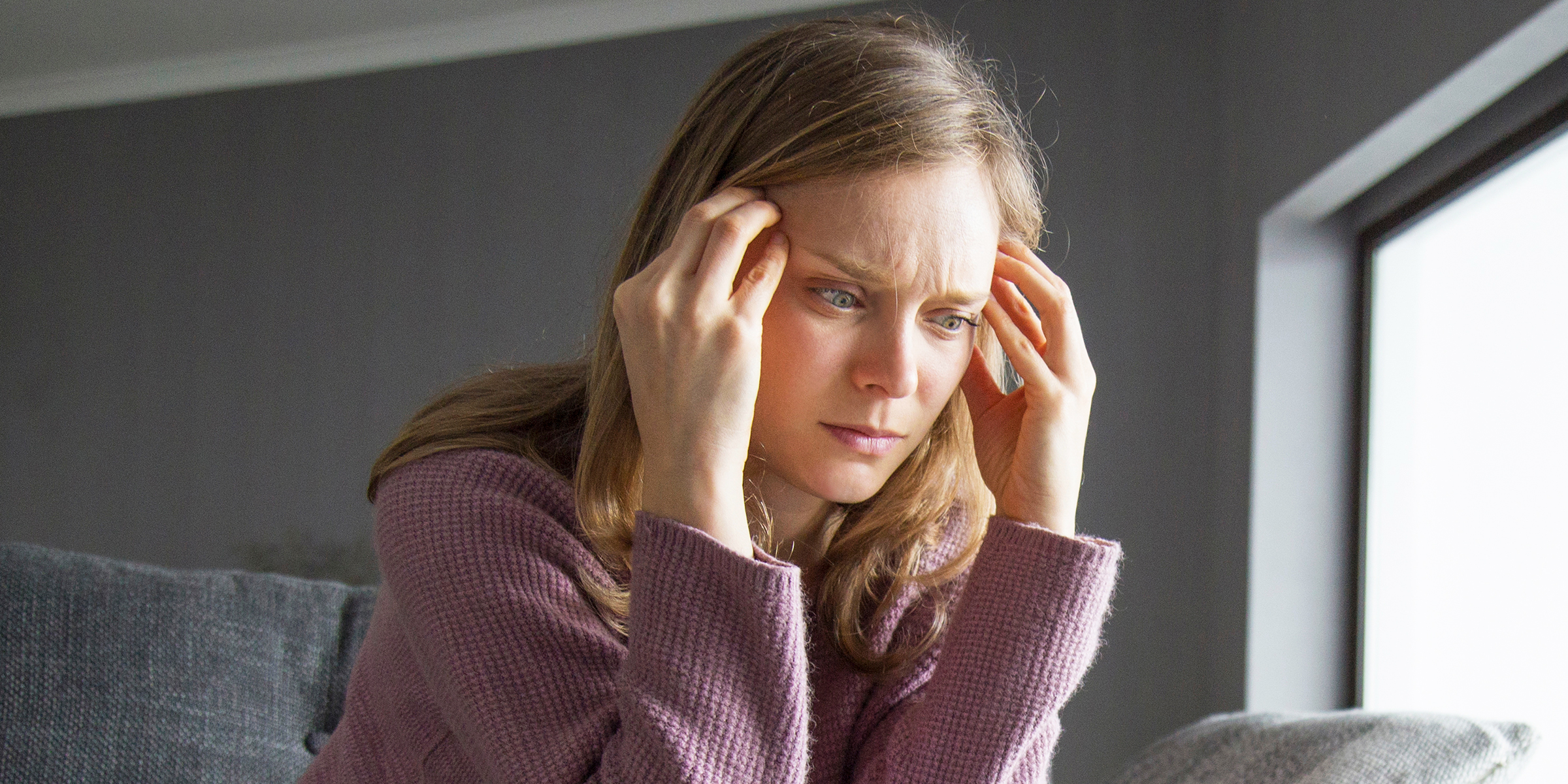 Eine besorgte Frau drückt ihre Finger an ihre Schläfen | Quelle: Shutterstock