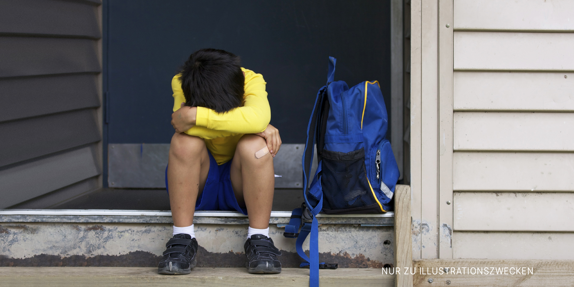 Junge sitzt auf einer Türschwelle | Quelle: Getty Images