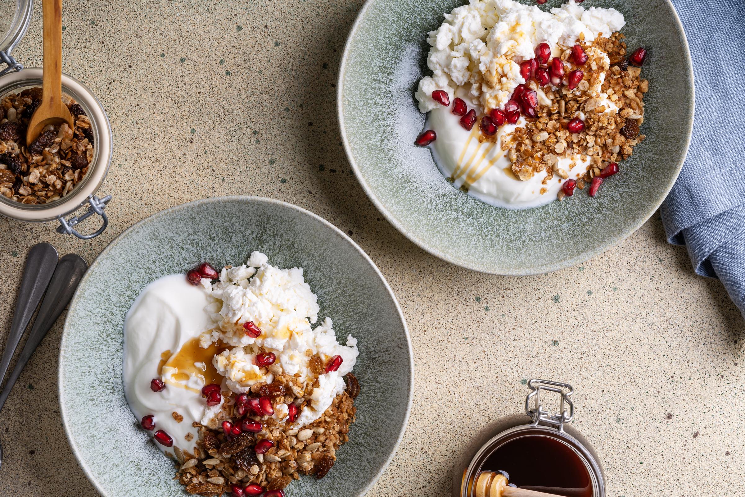 Selbstgemachtes Müsli mit Hüttenkäse, Kefir, Granatapfel und Honig in einer Schüssel | Quelle: Getty Images