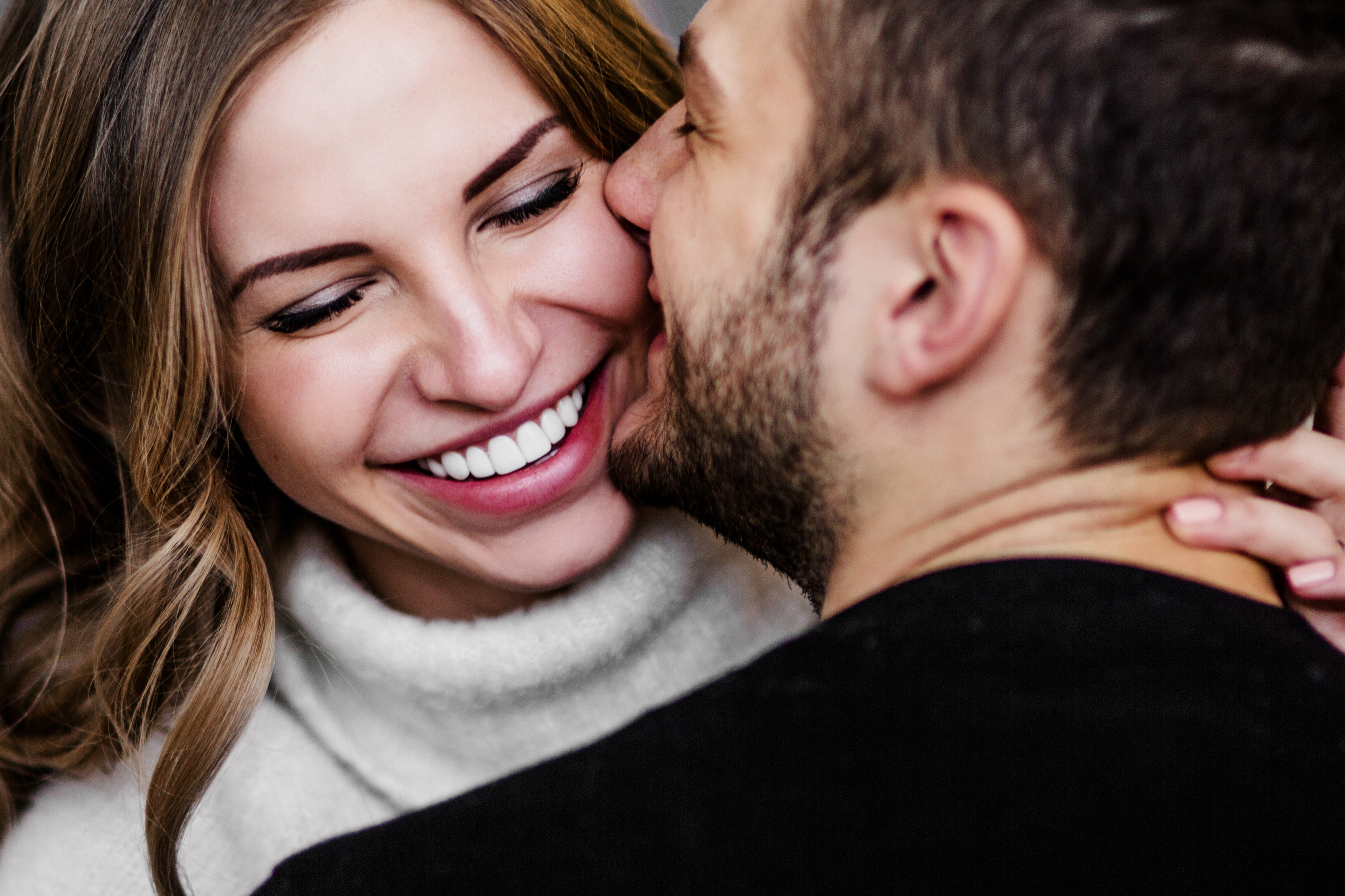 Ein Mann küsst seine lächelnde Partnerin auf die Wange | Quelle: Shutterstock