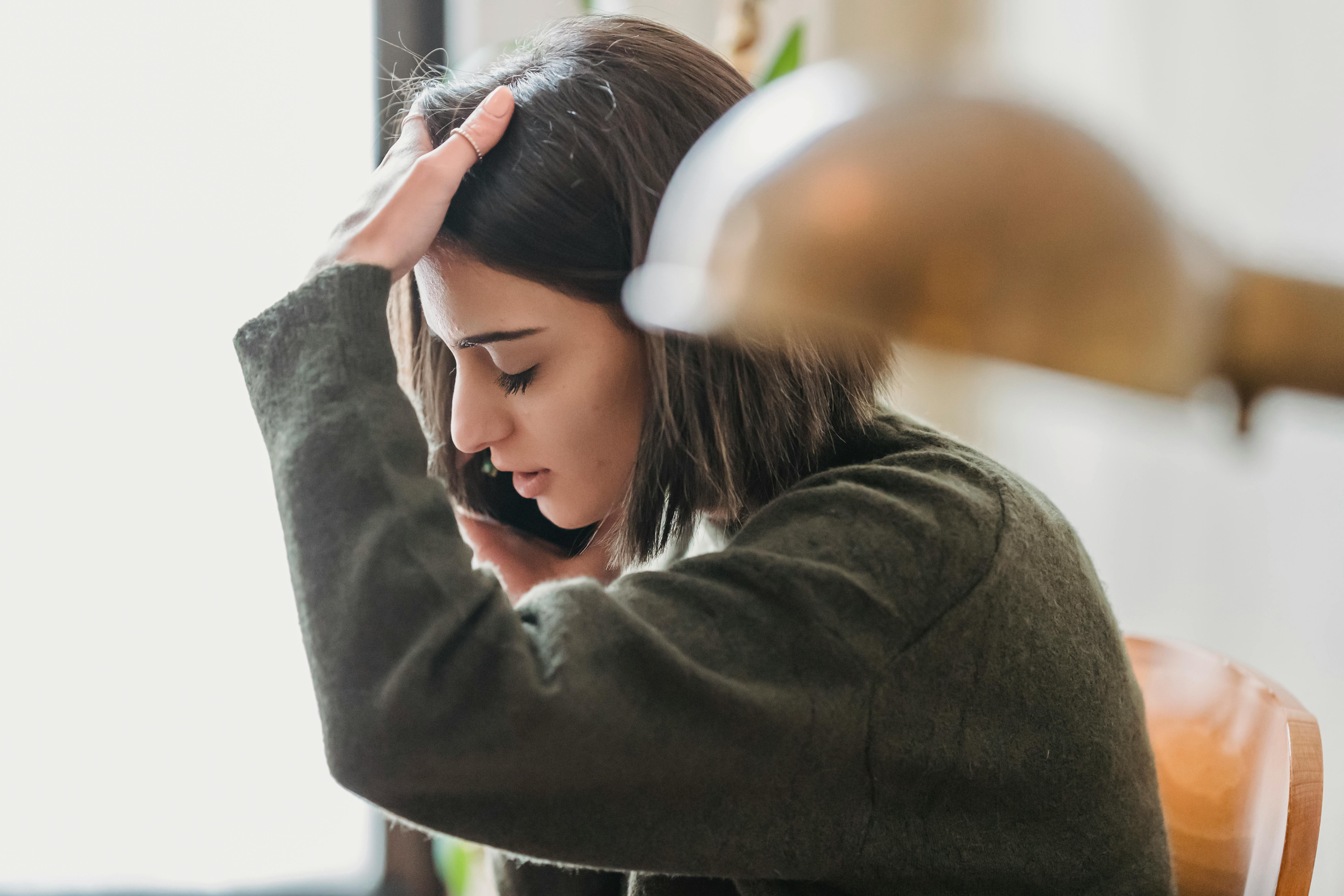 Eine enttäuschte junge Frau, die ihren Kopf beim Telefonieren berührt | Quelle: Pexels