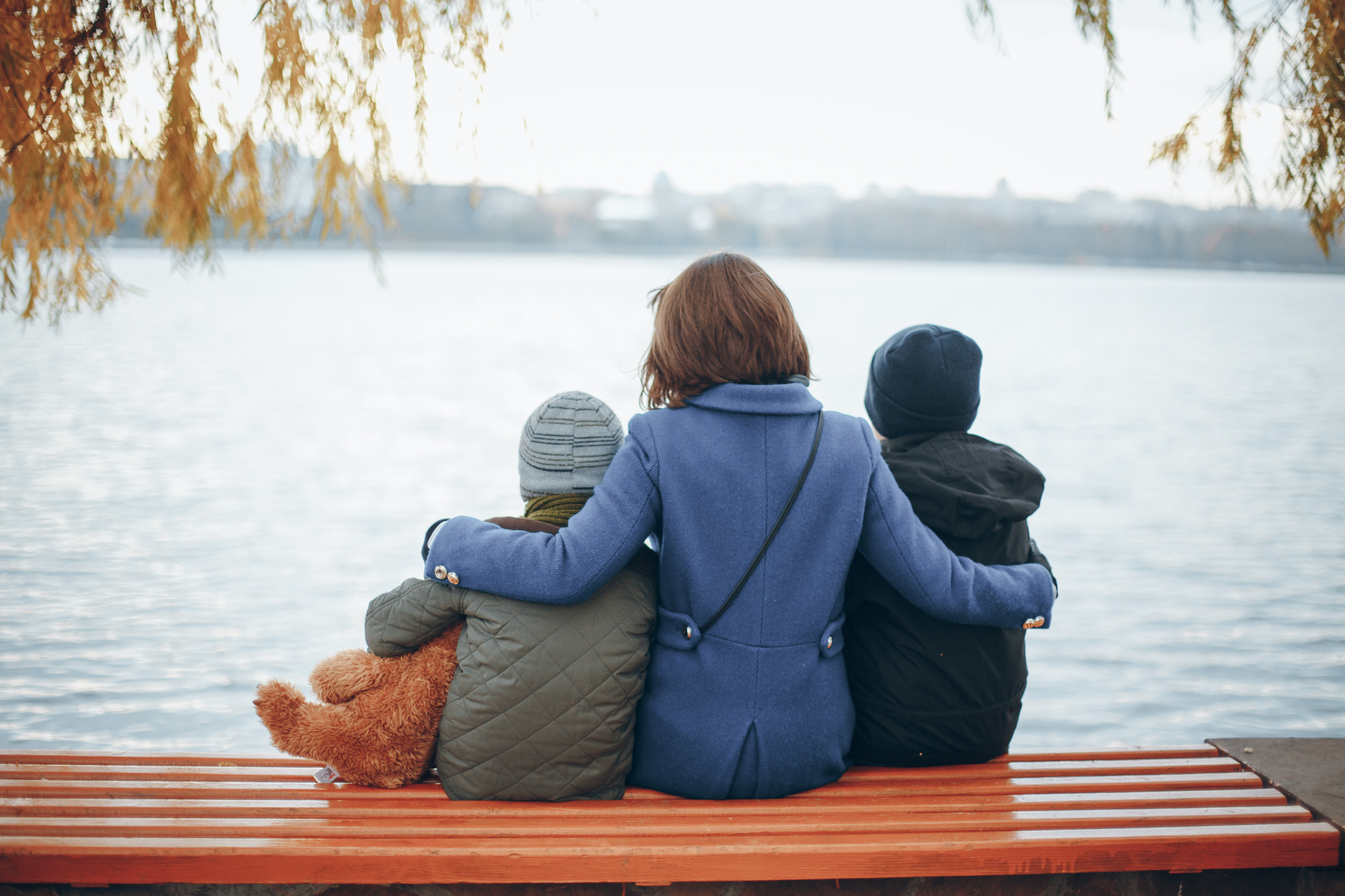 Eine Frau sitzt mit ihren beiden Kindern in der Nähe des Flusses | Quelle: Shutterstock