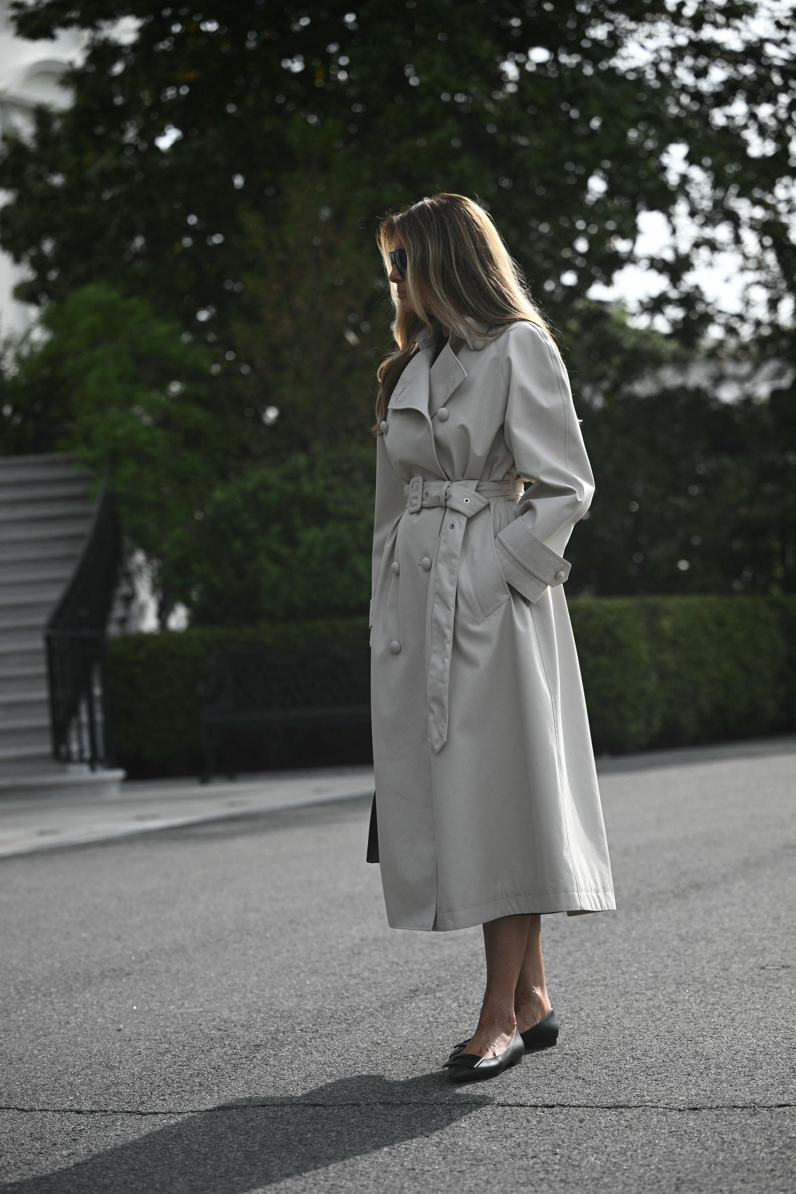 First Lady Melania Trump steht am 25. April 2025 auf dem South Lawn des Weißen Hauses in Washington, D.C., auf dem Weg zur Joint Base Andrews, von wo aus es weiter nach Rom geht. Sie trägt einen doppelreihigen Trenchcoat in Steinfarbe mit Gürtel und eine dunkle Sonnenbrille, dazu schlichte schwarze Lederballerinas mit spitzer Zehenpartie, die ihrer Reisegarderobe einen funktionalen, eleganten Touch verleihen.