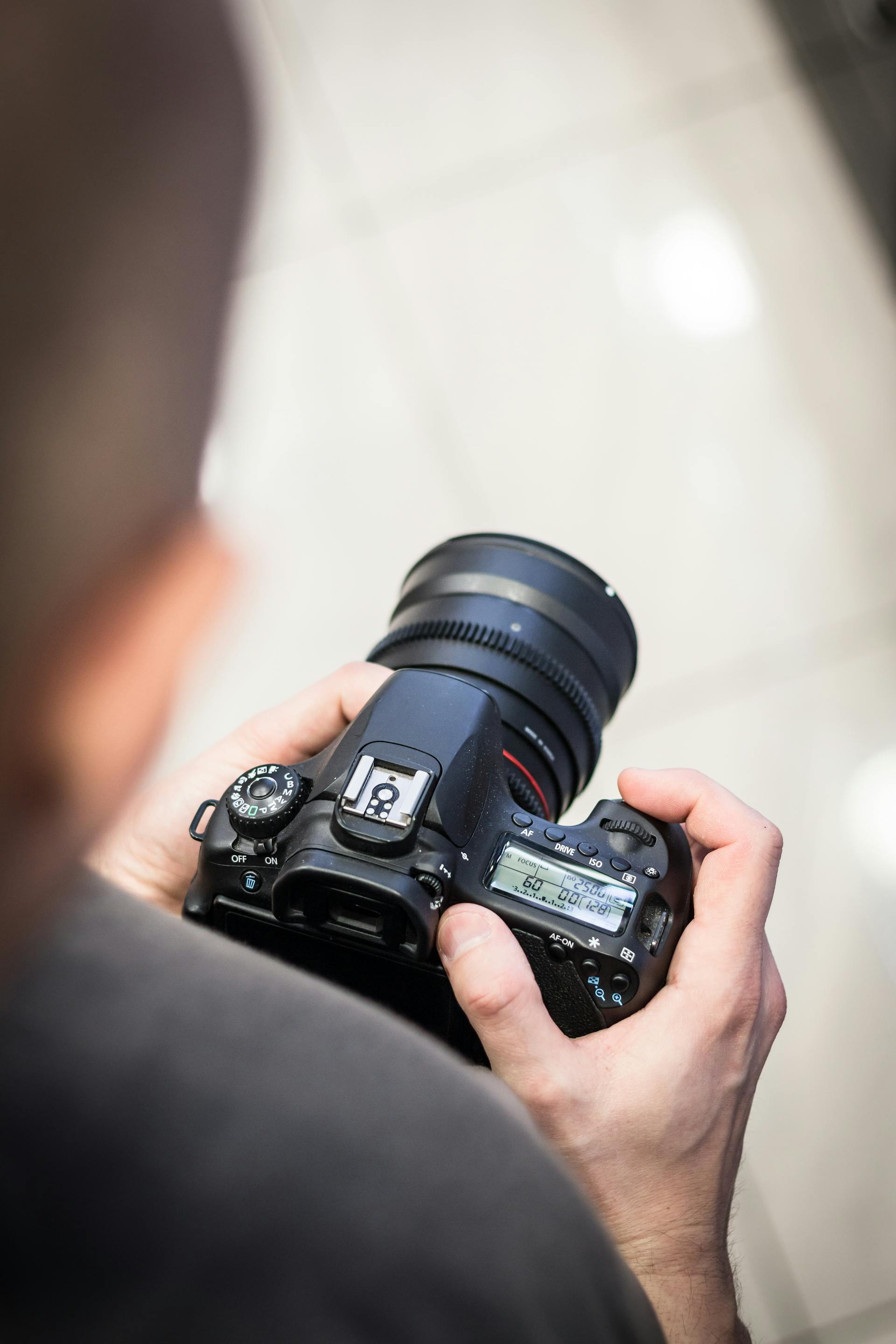 Ein Mann hält eine DSLR-Kamera | Quelle: Pexels