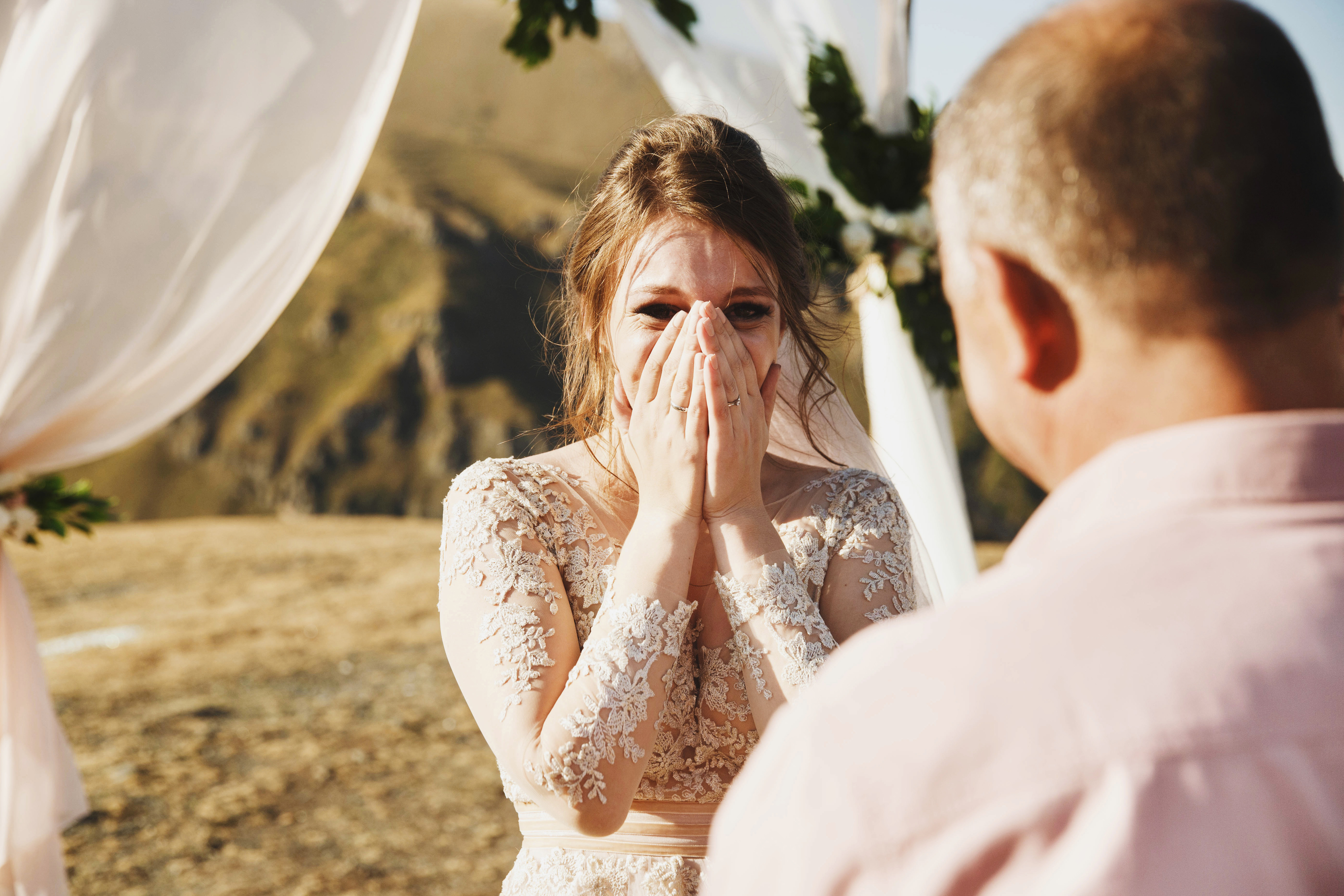 Eine Braut schaut ihren Vater an, während sie sich mit den Händen den Mund zuhält. | Quelle: Shutterstock