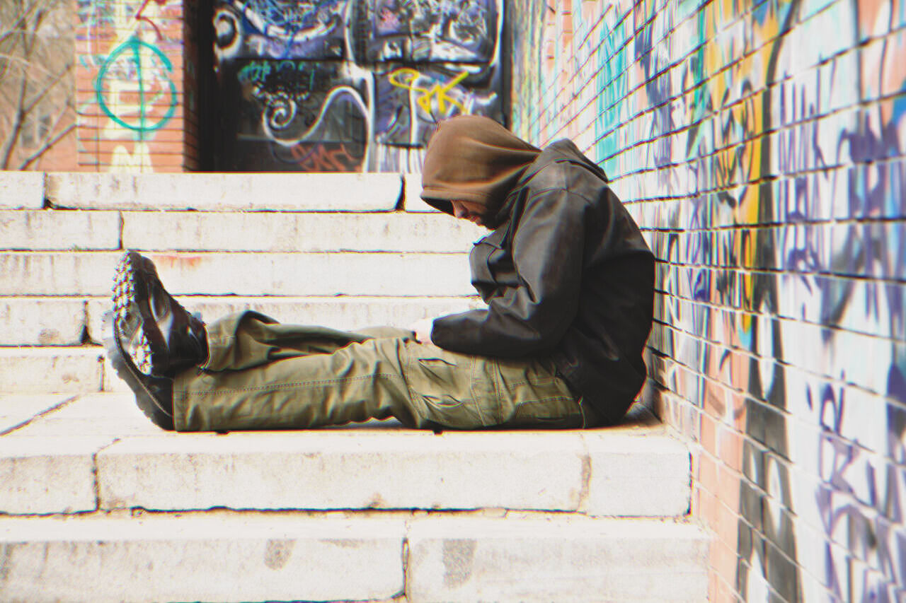 Obdachloser Mann, der auf der Straße sitzt | Quelle: Shutterstock