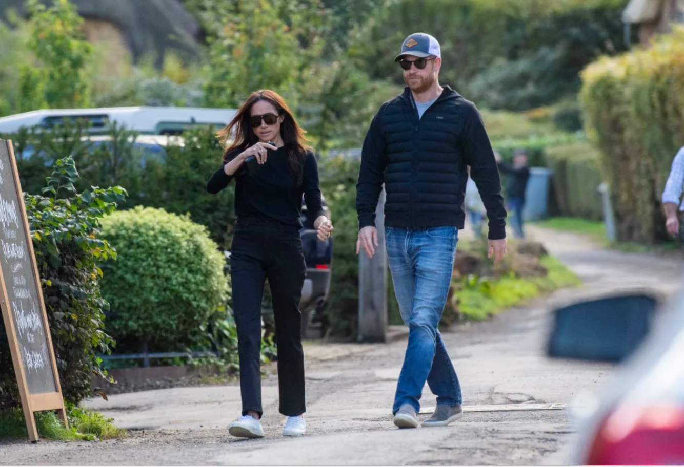 Prinz Harry und Meghan Markle spazieren am 1. Oktober 2026 Hand in Hand auf einem Feldweg in den Cotswolds – beide sind für ihren Pub-Besuch leger gekleidet. Harry trägt eine Baseballkappe und eine Sonnenbrille, während Meghan gestikuliert, als sie auf den historischen Pub zugehen. | Quelle: Facebook/Prinz Harry, Herzog von Sussex