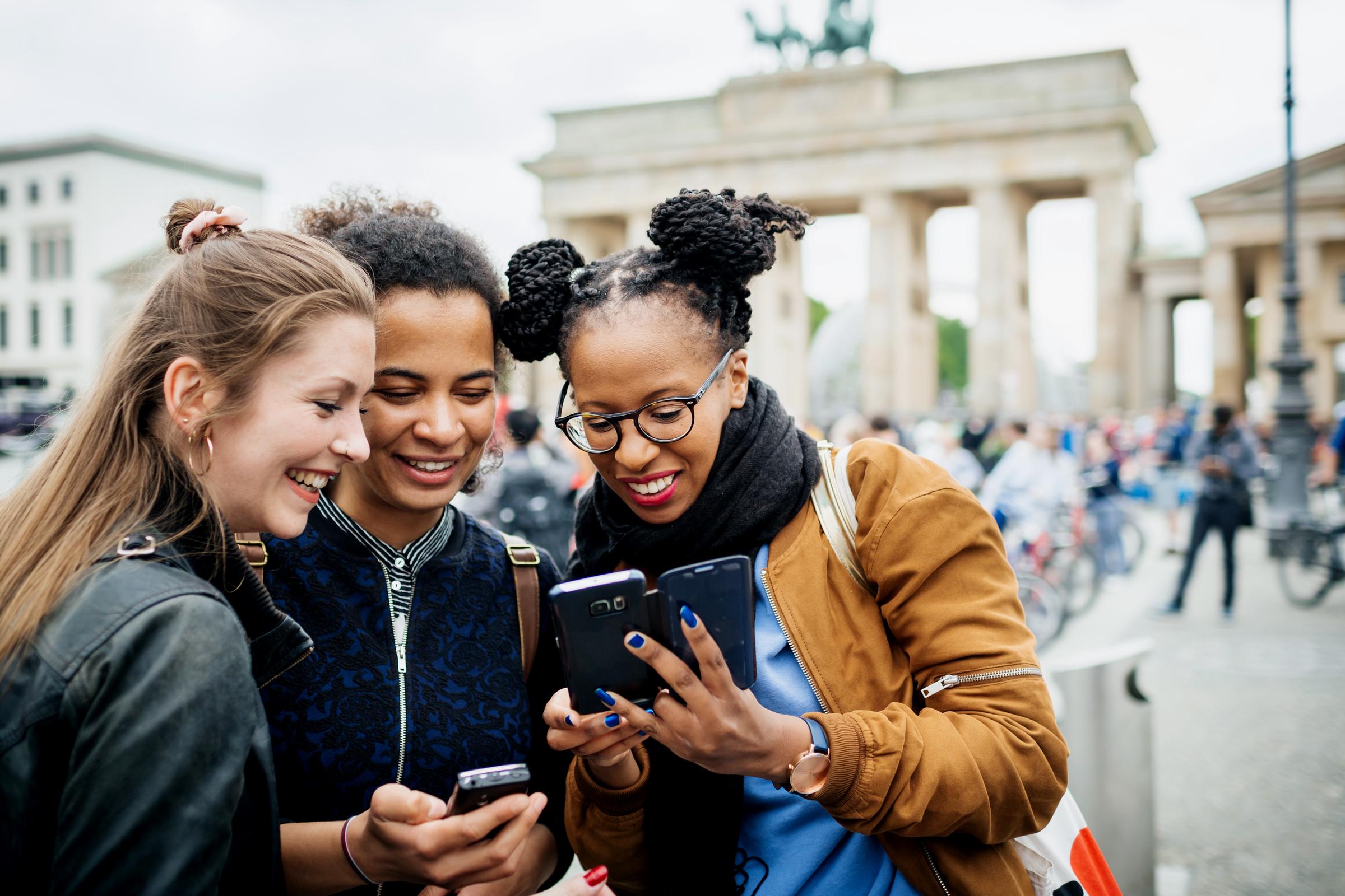 Eine Gruppe von Freunden, die zusammen unterwegs sind und einen Zwischenstopp einlegt, um etwas online zu checken | Quelle: Getty Images