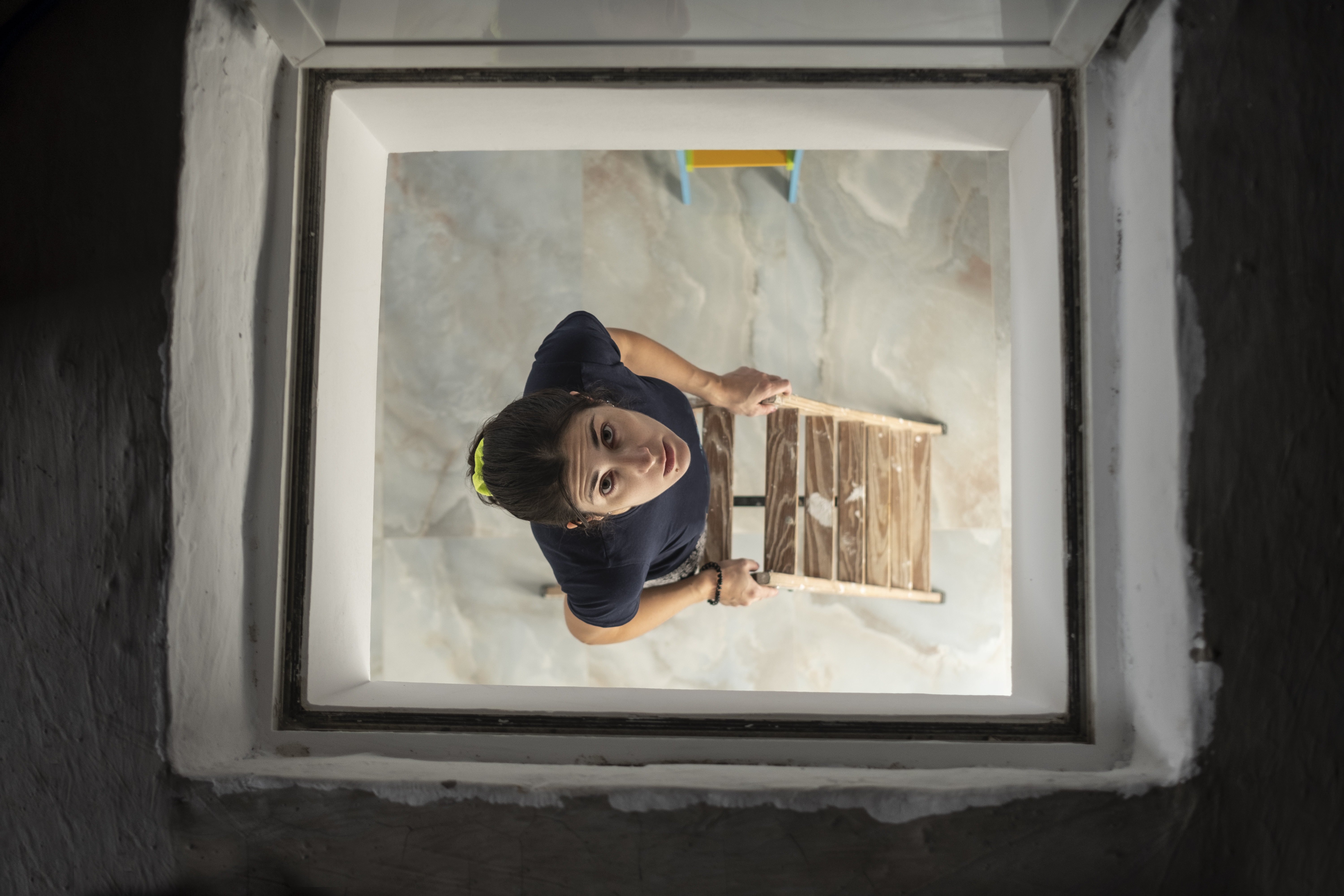 Frau späht durch die Luke der Dachbodentreppe | Quelle: Getty Images