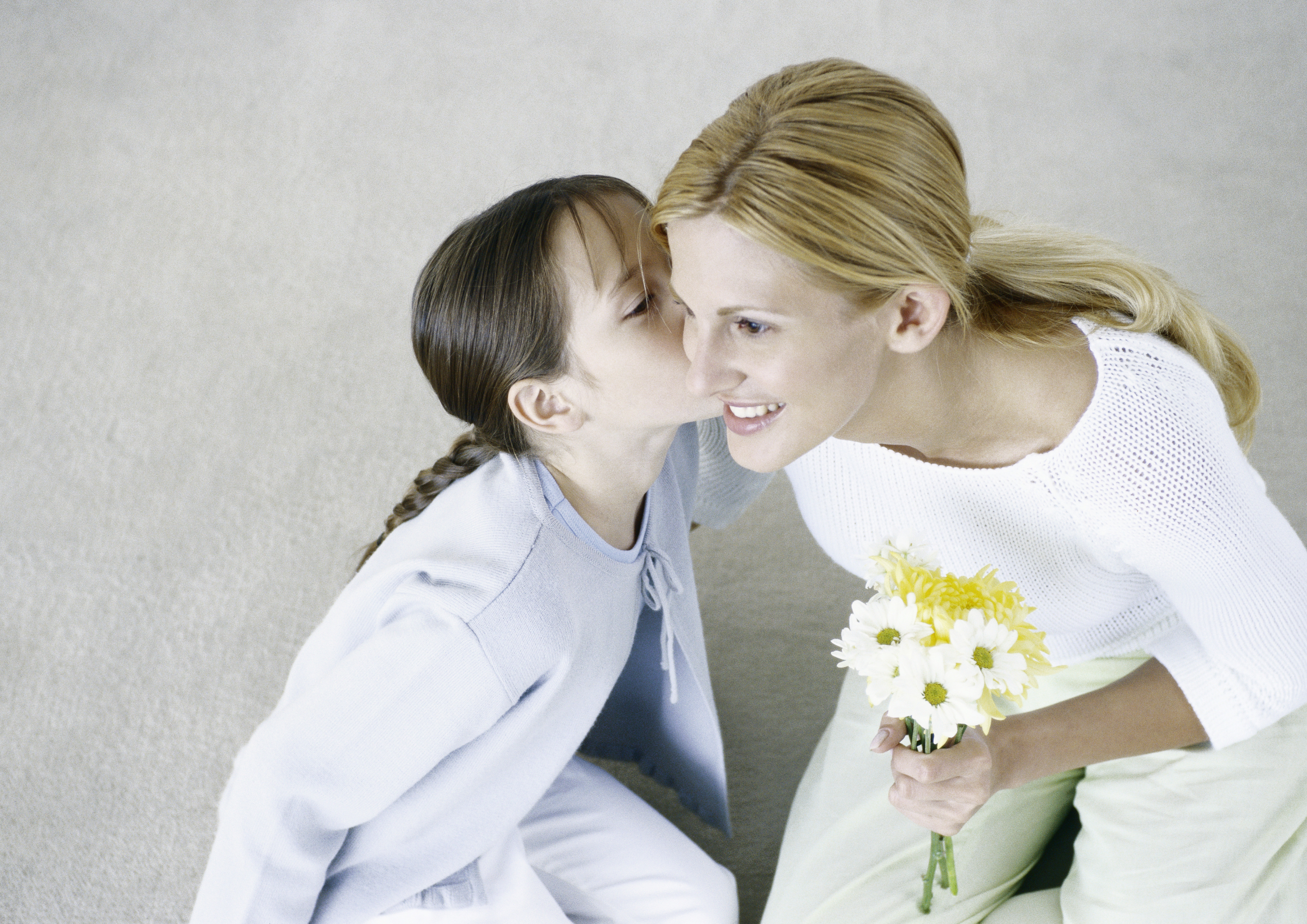 Frau hält Blumenstrauß, Mädchen küsst ihre Wange | Quelle: Getty Images