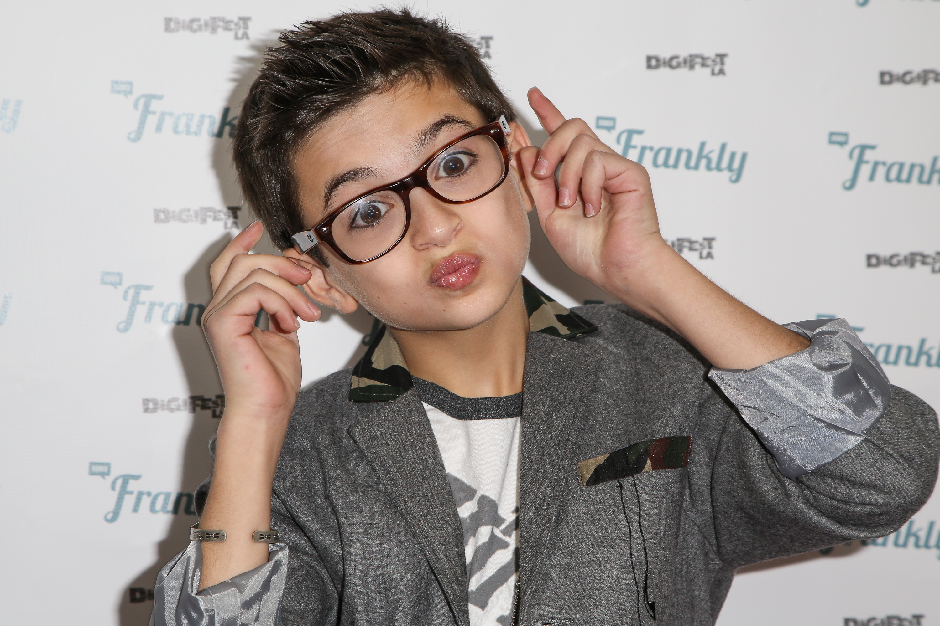 Sie posiert verspielt beim DigiFest LA im Hollywood Palladium in Hollywood, Kalifornien, und trägt eine übergroße Brille mit dunklem Rahmen, einen grauen Blazer mit Camouflage-Akzenten und ein T-Shirt mit Aufdruck. | Quelle: Getty Images