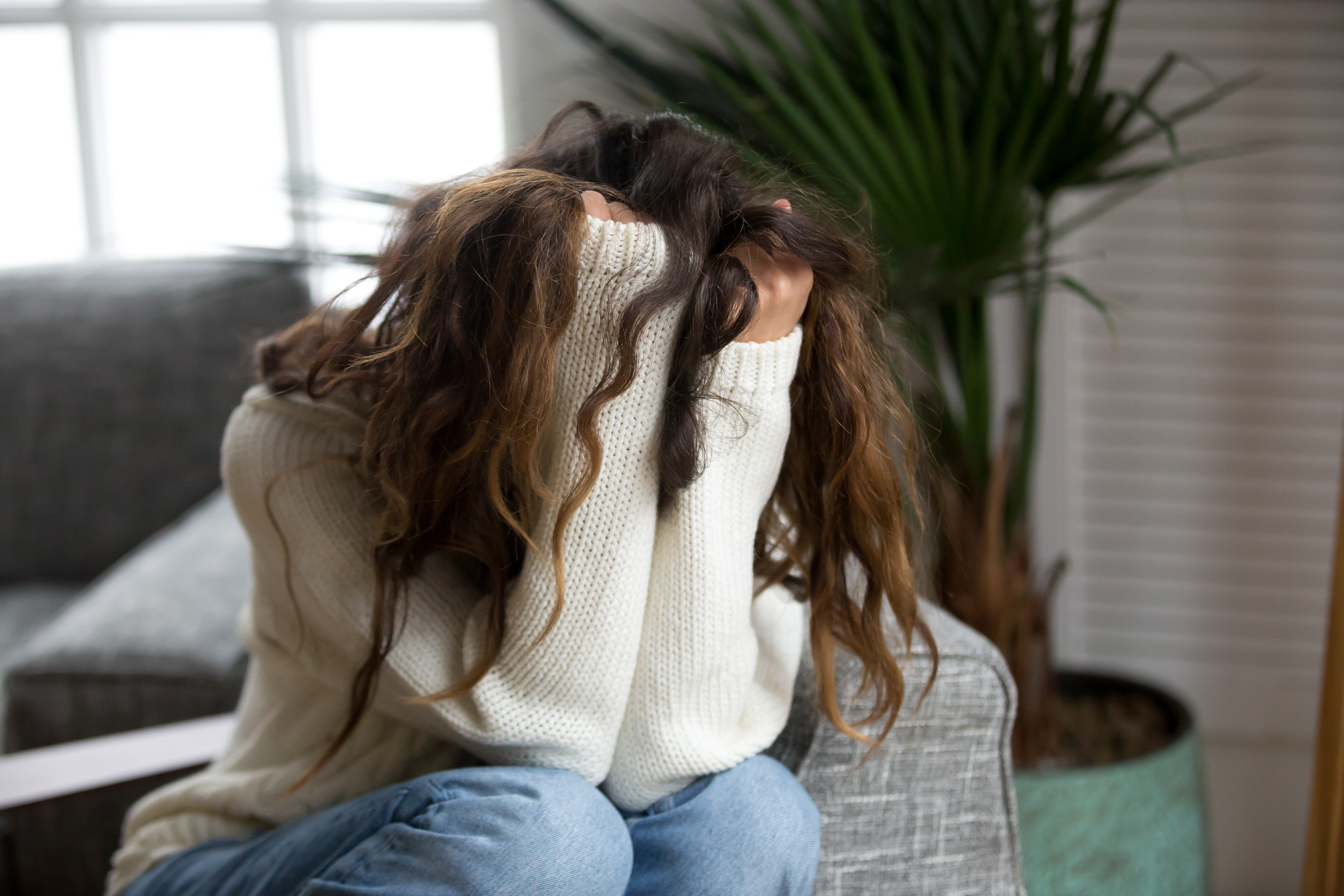 Eine depressive Frau, die ihr Gesicht mit ihren Händen versteckt | Quelle: Shutterstock