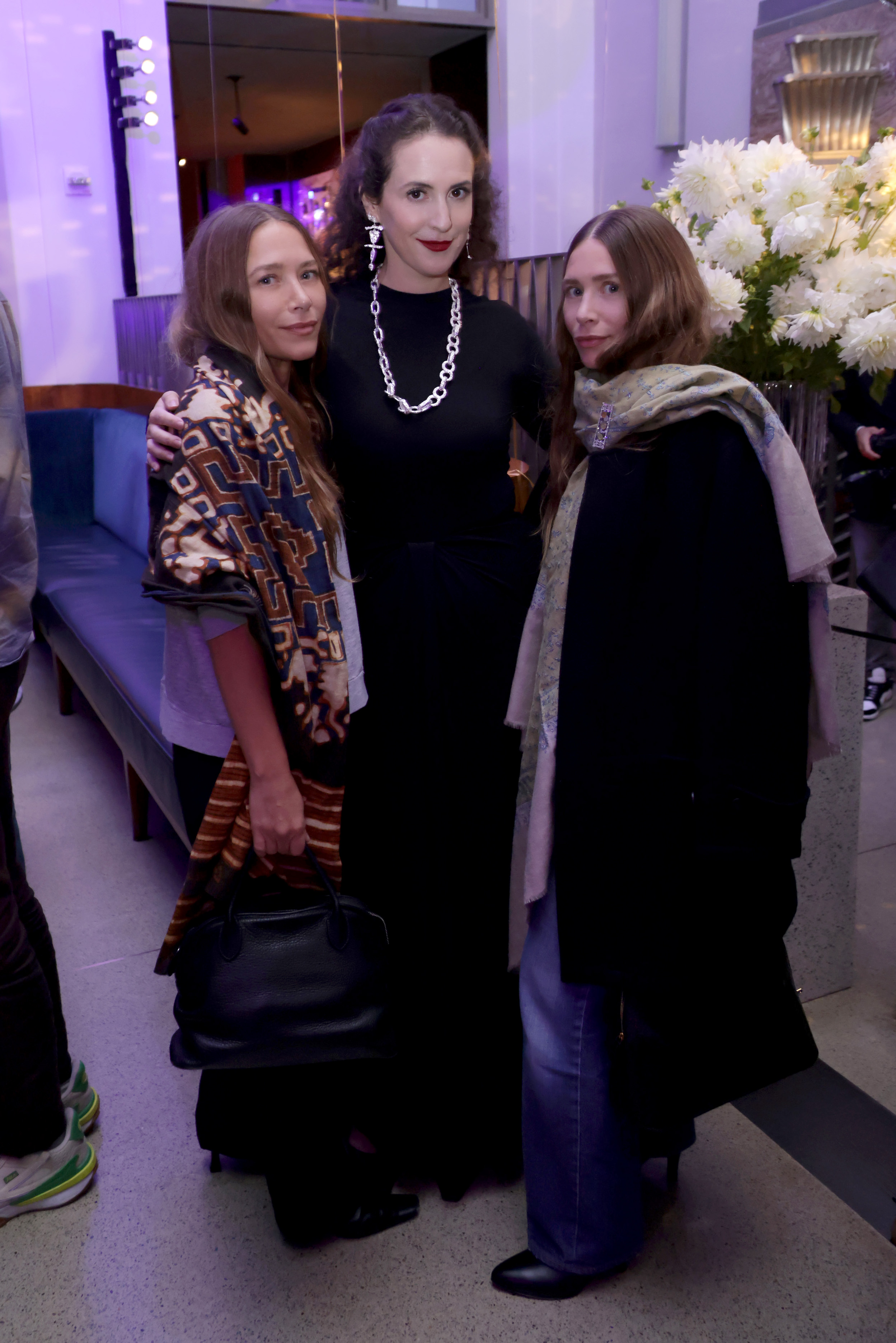 Ein natürliches Lächeln und entspannte Gesichtsausdrücke zierten die 39-jährigen Mary-Kate und Ashley Olsen an der Seite von Sara Moonves bei einer Feier im Rahmen der New York Fashion Week im Restaurant „Eleven Madison Park“ am 11. September 2025, wo Mary-Kate einen gemusterten Schal über einem dunklen Outfit trug, dazu eine schwarze Handtasche, und Ashley trug lockere blond-braune Locken, die von einem gemusterten Schal umrahmt wurden, dazu einen dunklen Mantel und blaue Jeans.